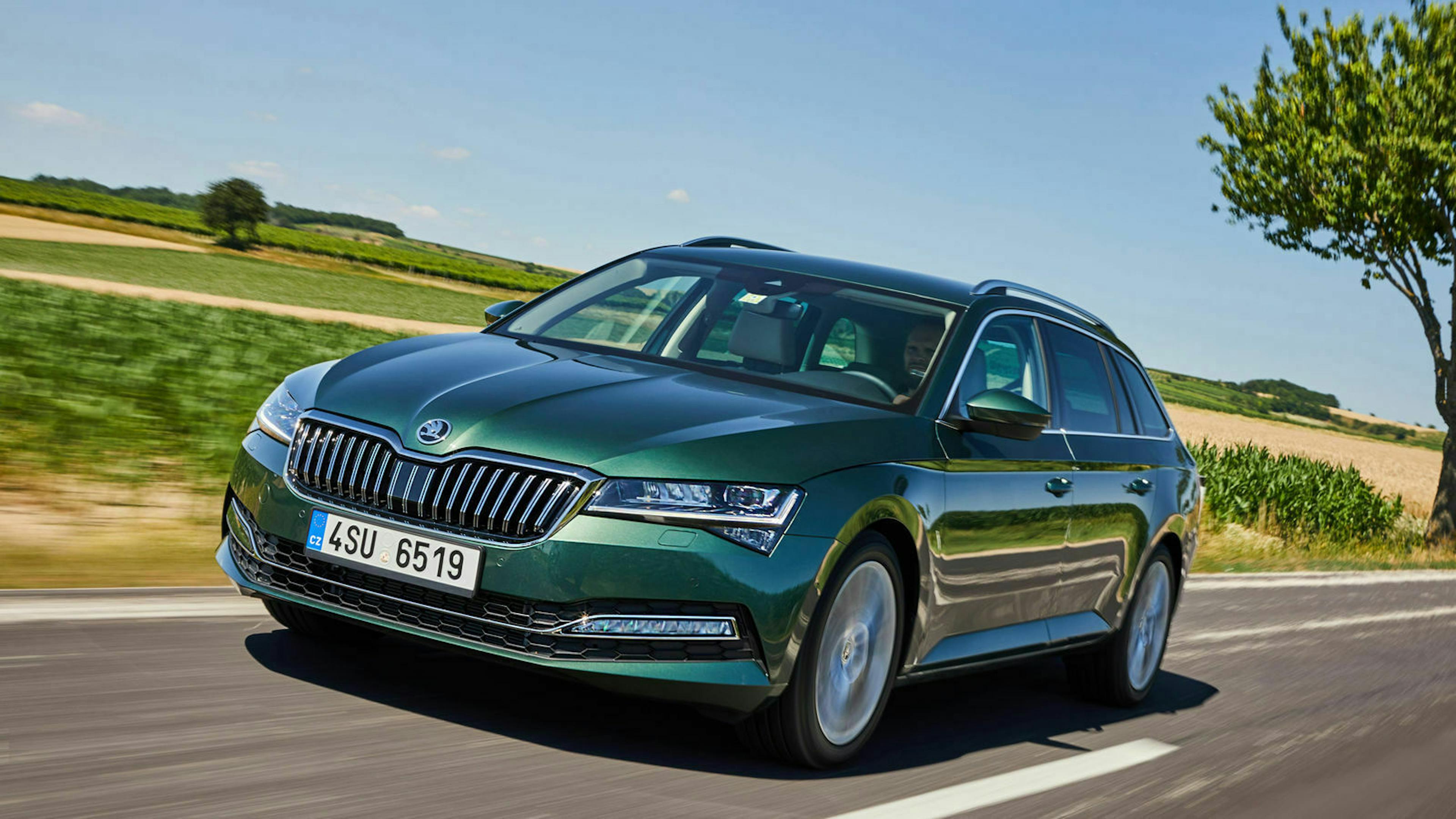 Ein dunkelgrüner Skoda Superb fährt auf einer Landstraße