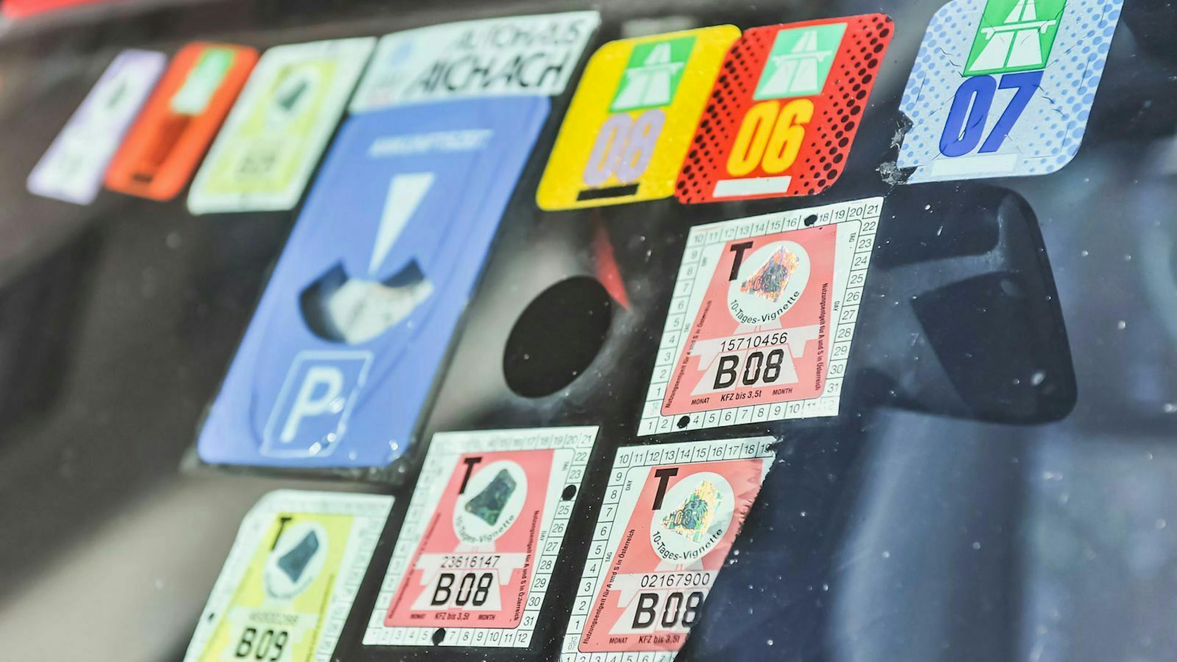 In einer PKW-Windschutzscheibe kleben etliche abgelaufene Mautvignetten.