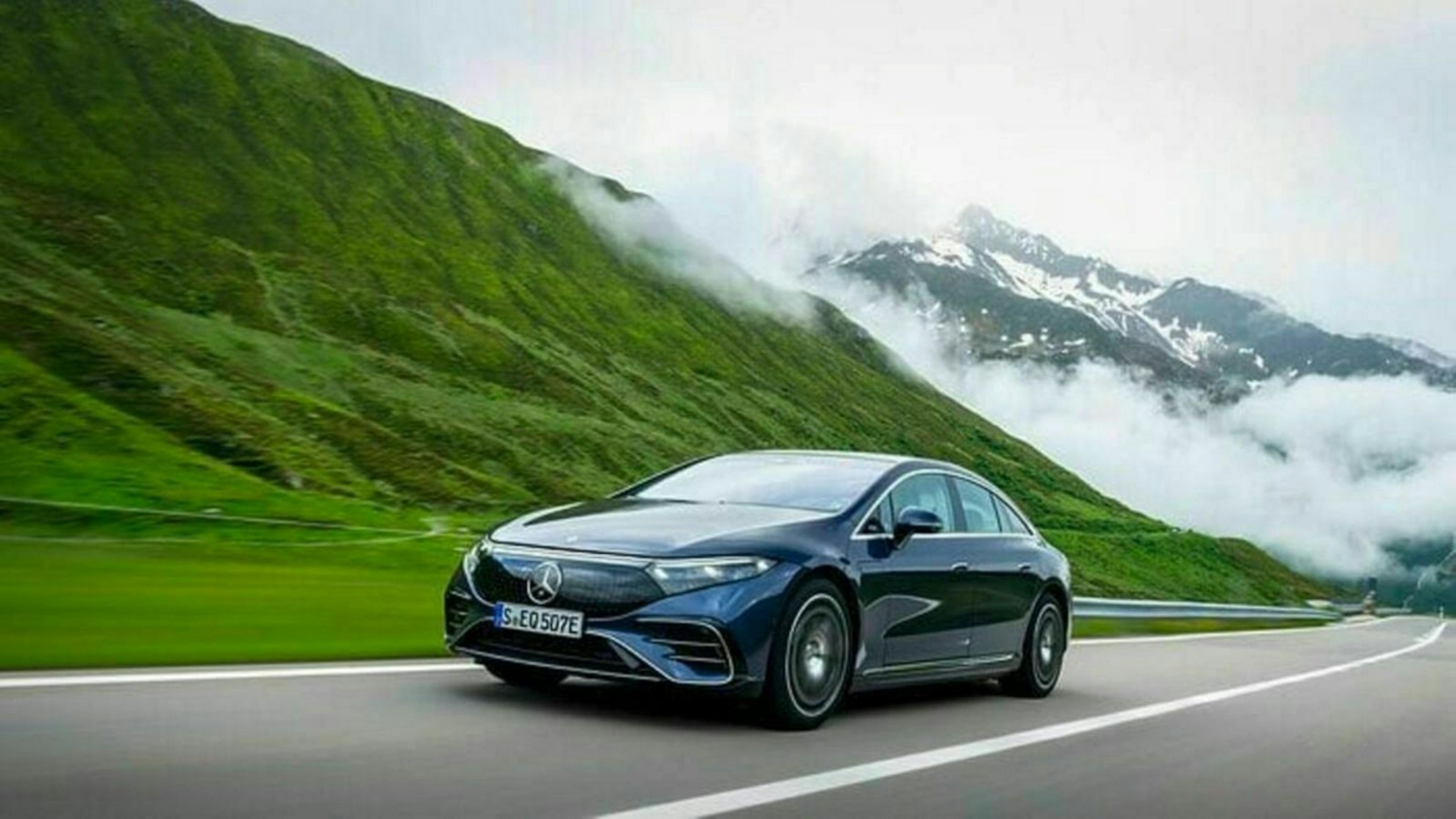 Ein schwarzer Mercedes-Benz EQS fährt über eine Landstraße