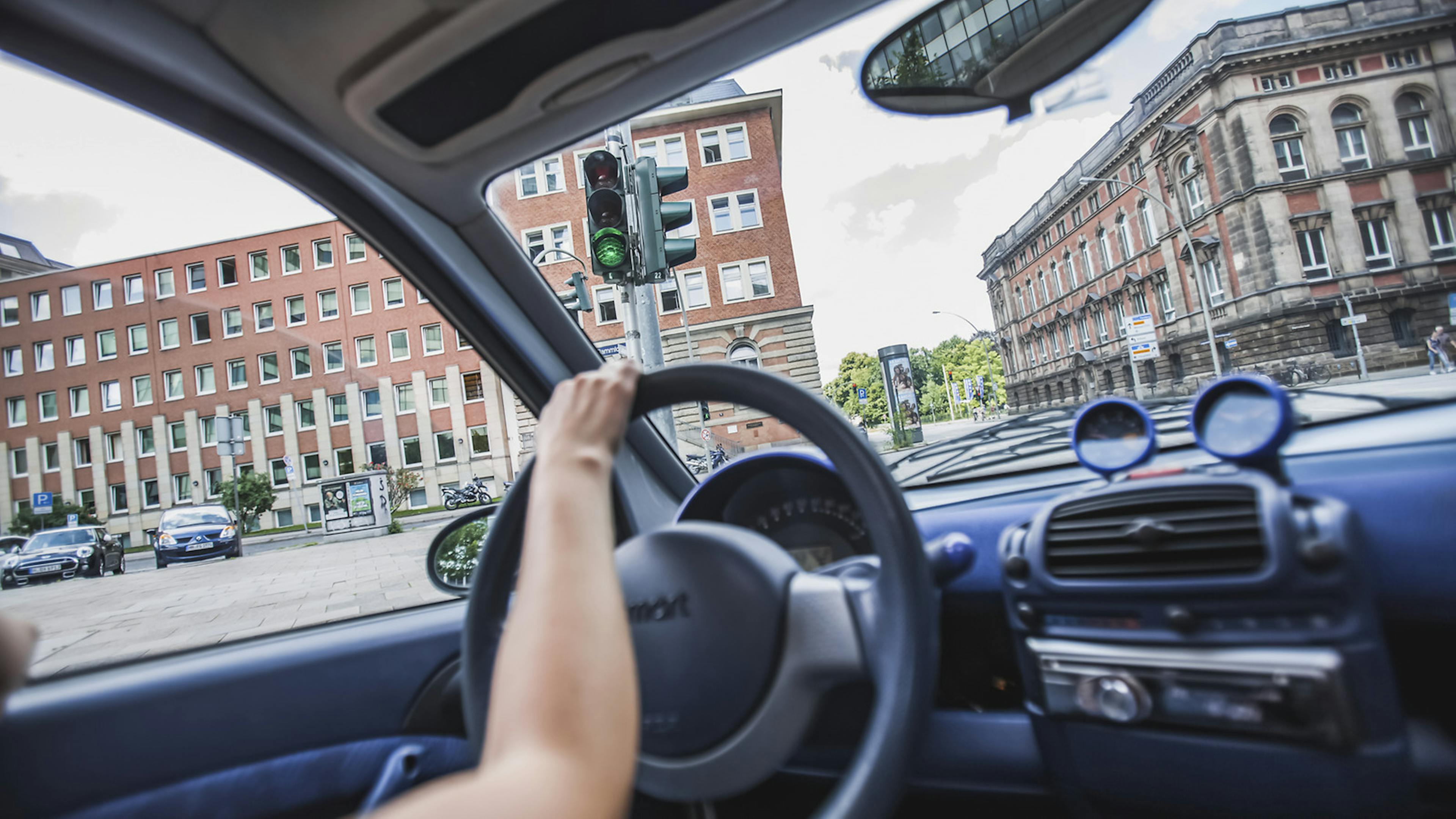 Jemand lenkt an einer grünen Ampel nach links und biegt in eine Straße ab