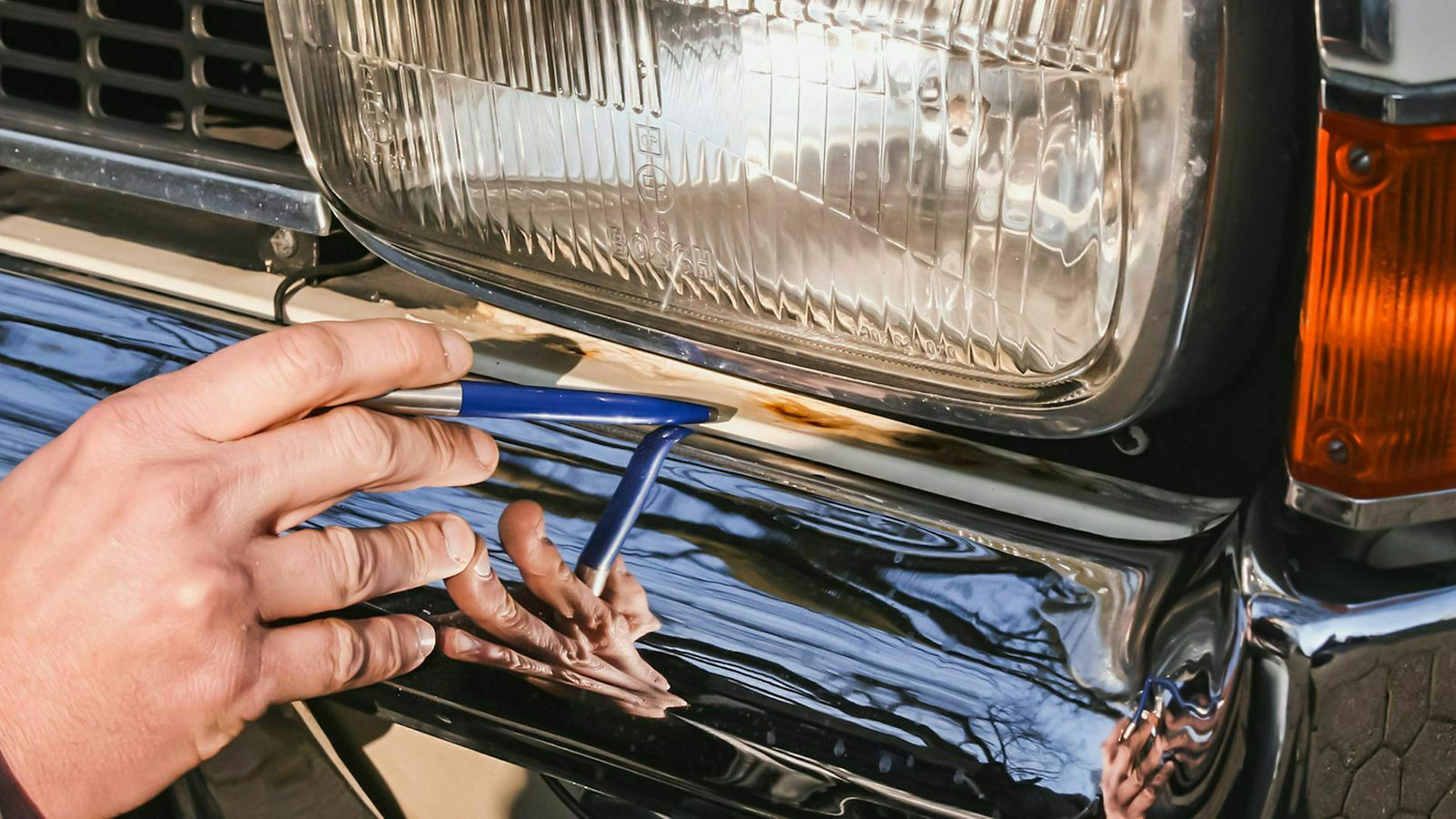 Prüfer zeigt mit einem Stift auf eine Stelle am Fahrzeug.