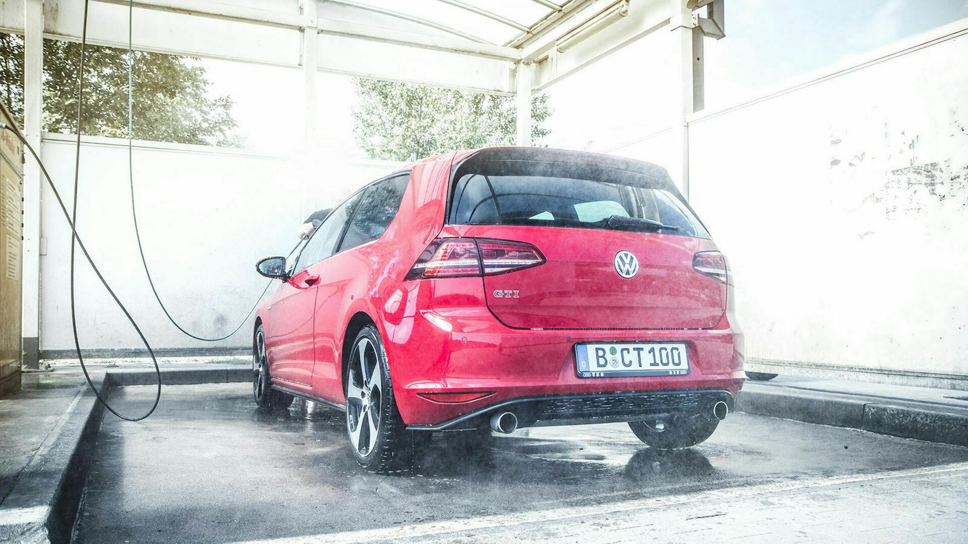 Ein roter VW Golf GTI steht in einer SB-Waschbox