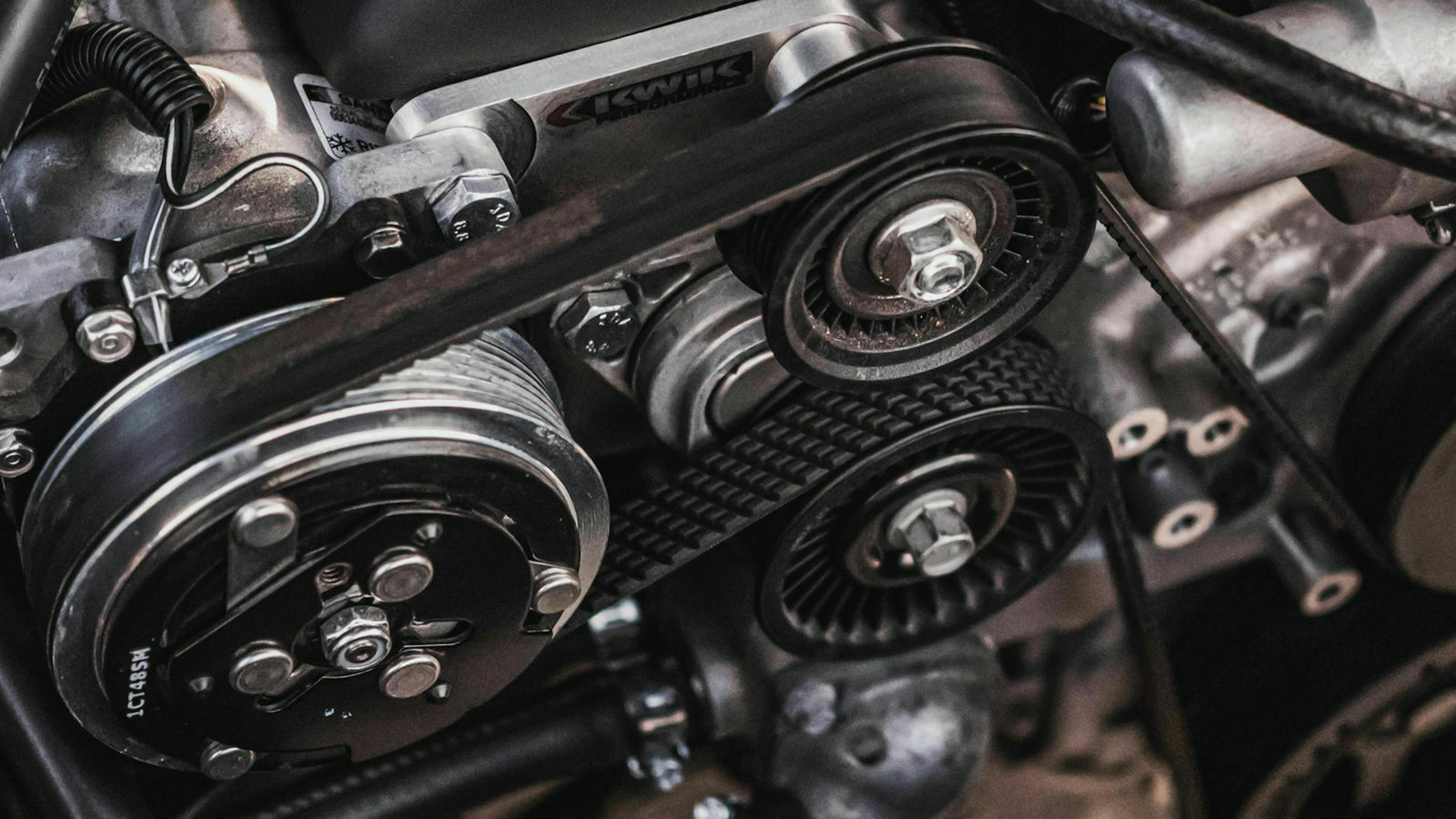 Ein Zahnriemen sitzt über Umlenkrollen gespannt an einem Motor in einem gepflegten Gebrauchtwagen