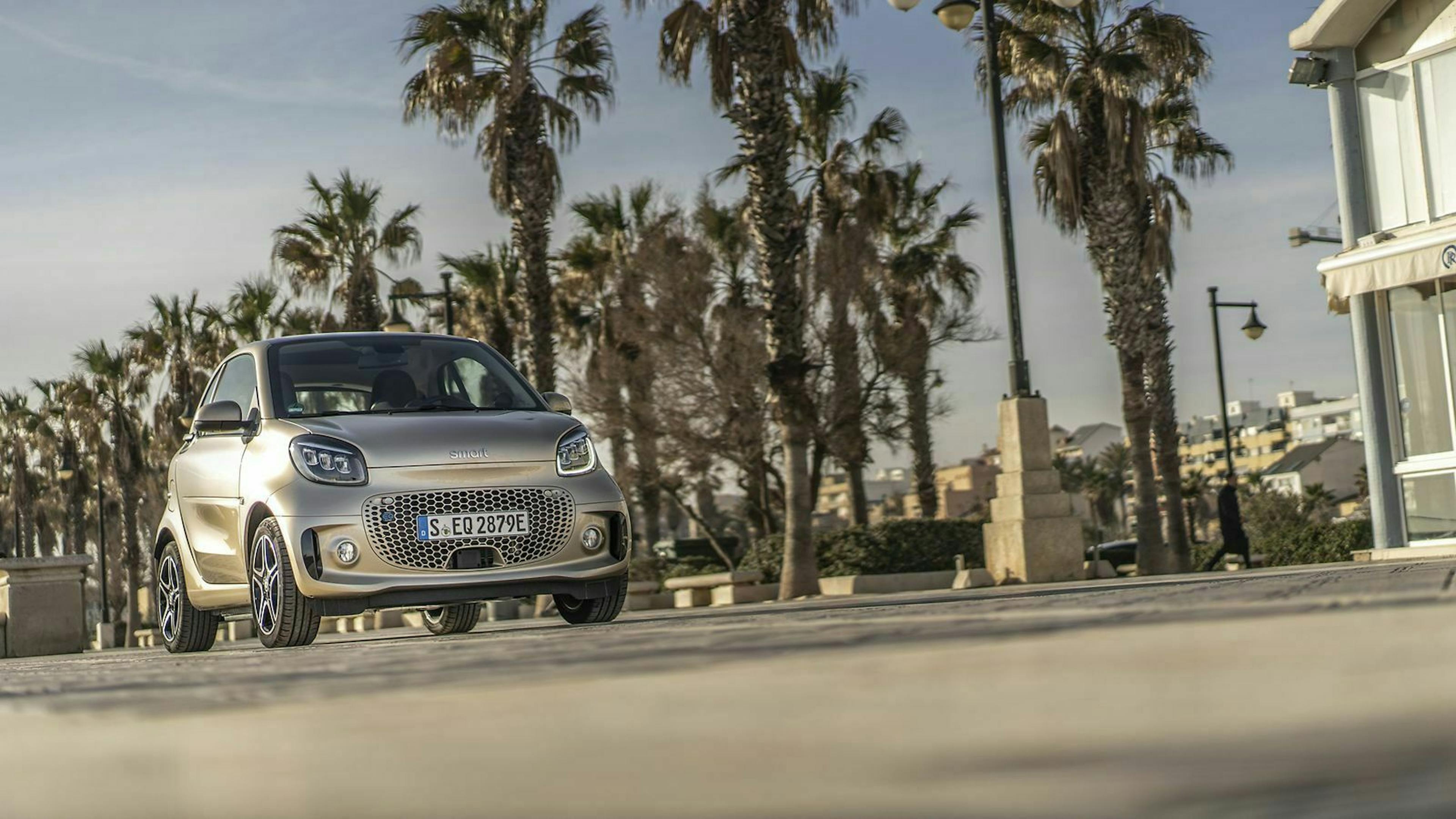 Zu sehen ist der Smart EQ ForTwo Coupe Gold Metallic, fahrend