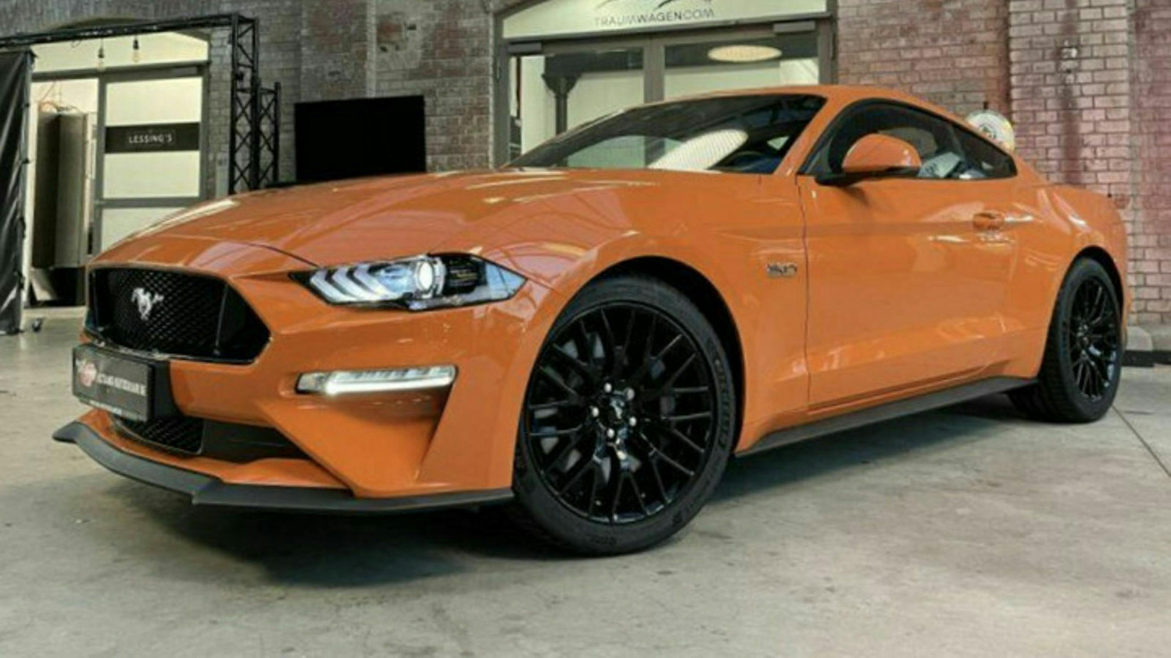 Ein orangefarbener Ford Mustang steht in einer Lagerhalle