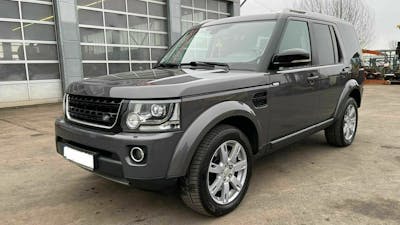 Ein grauer Land-Rover Discovery steht auf einem Parkplatz vor einer Lagerhalle