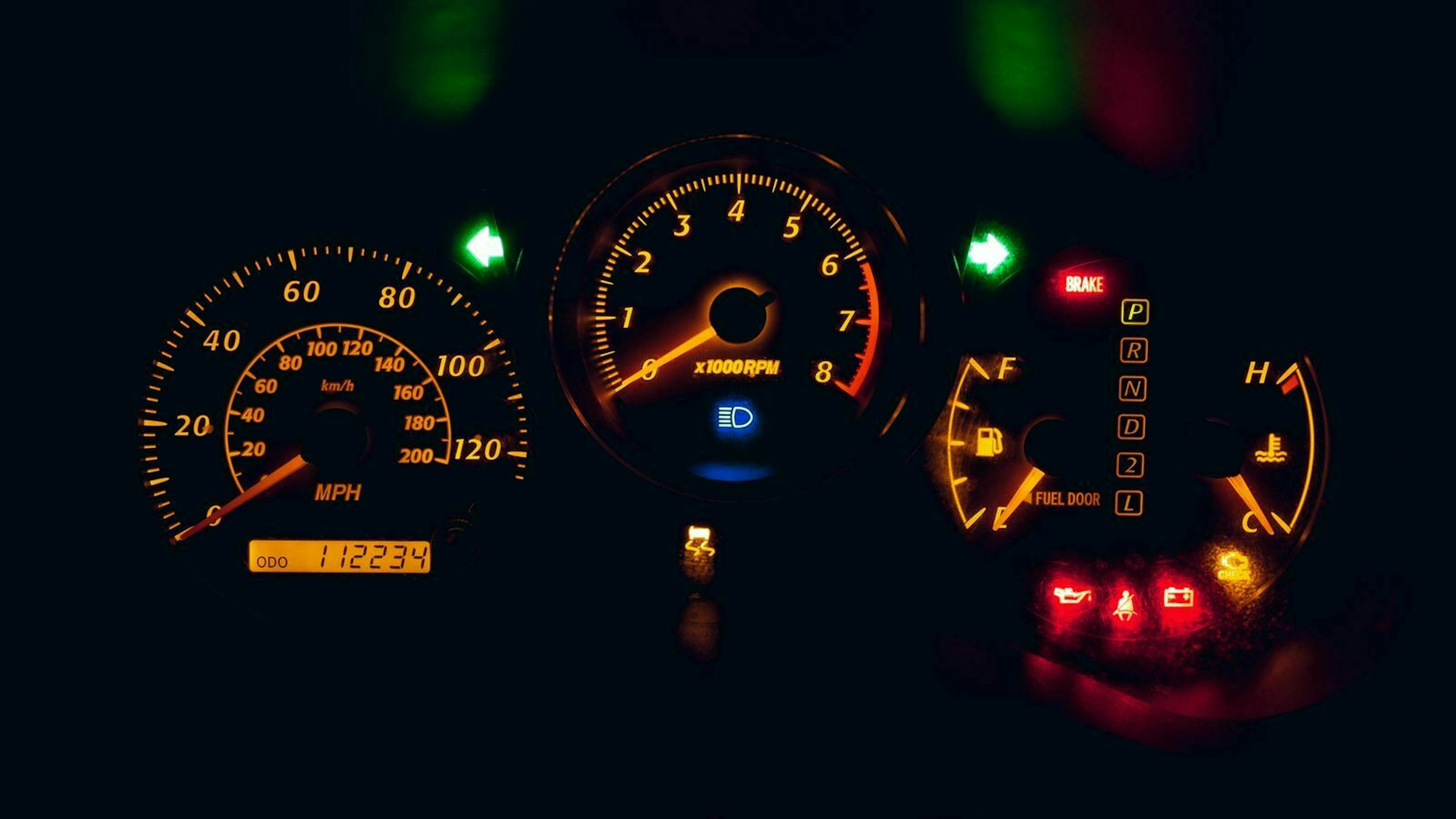 Detail of a car dashboard with speedometer and rev counter.