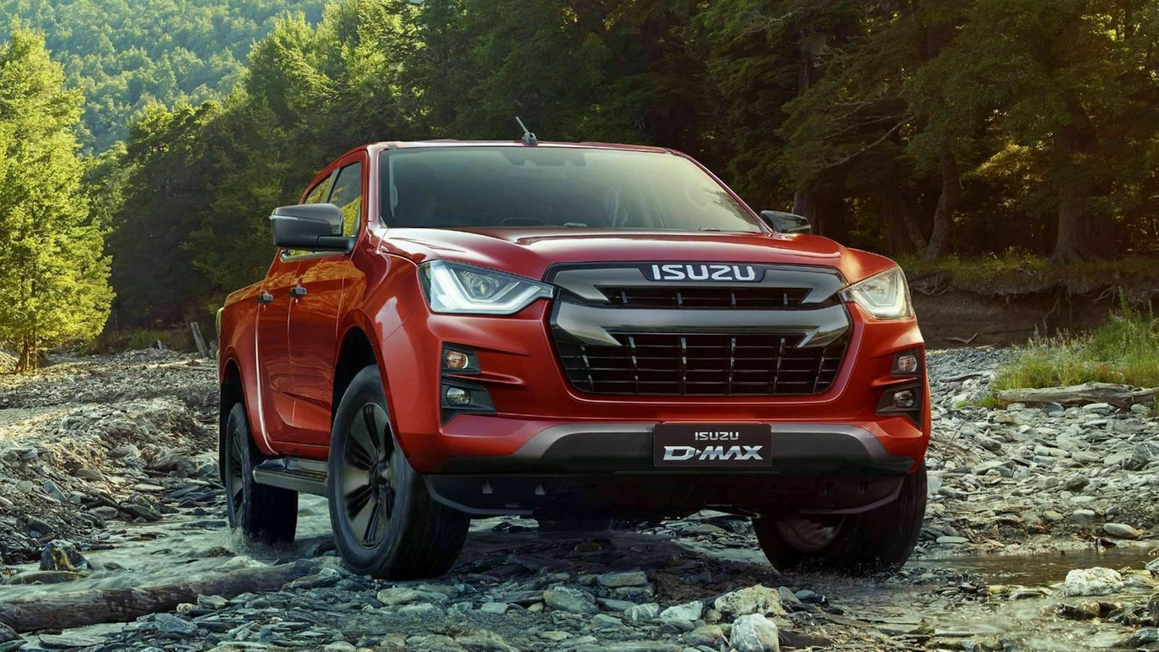 Ein roter Isuzu D-Max Pick-up fährt über ein trockenes Flussbett.