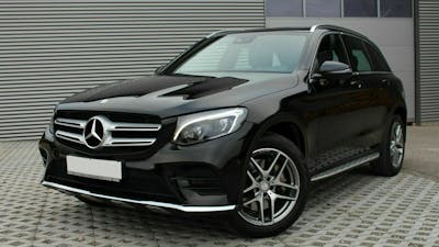 Ein schwarzer Mercedes-Benz GLC steht vor einem grauen Rolltor