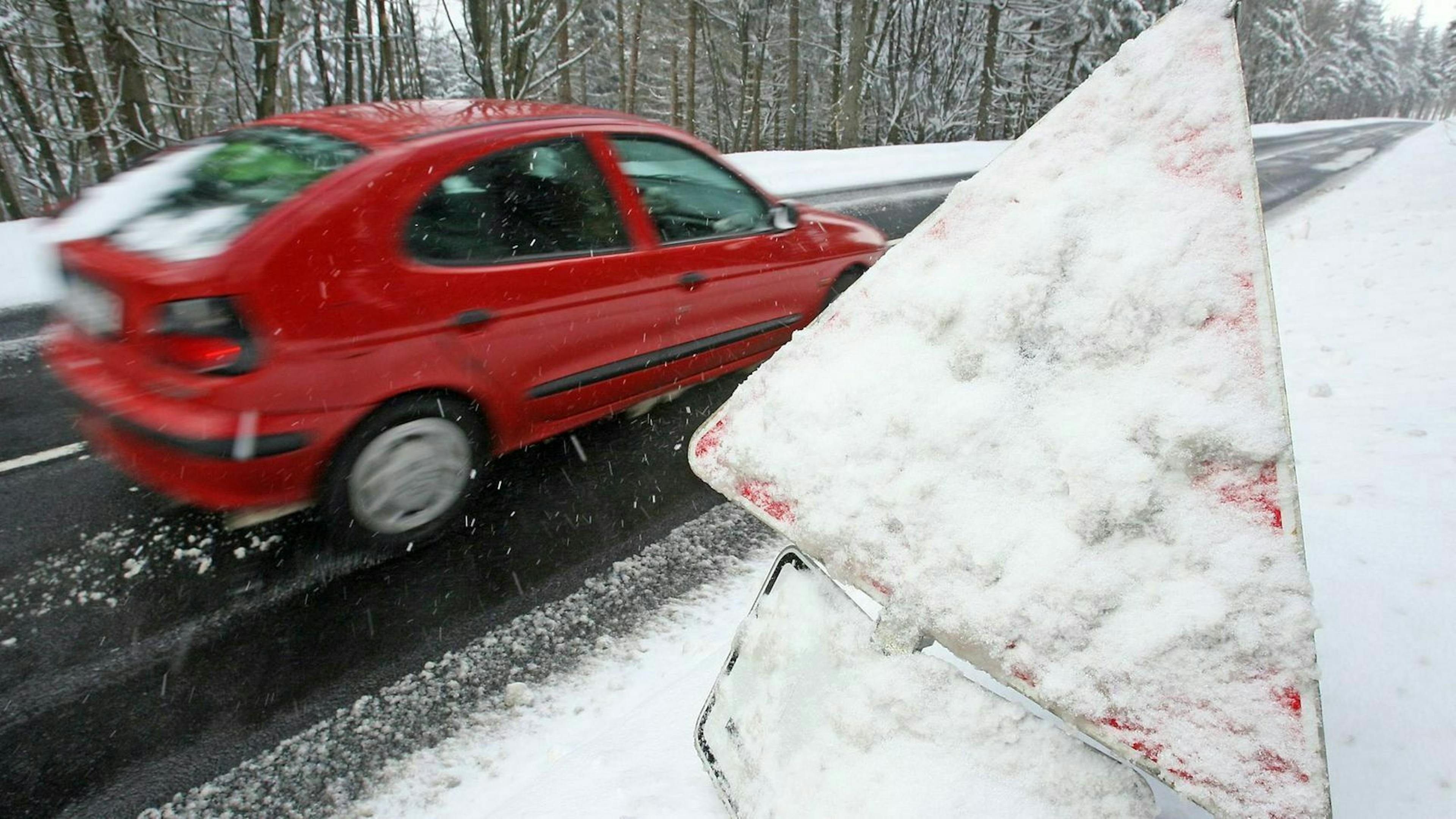 Auto fährt an zugeschneitem Verkehrsschild vorbei 