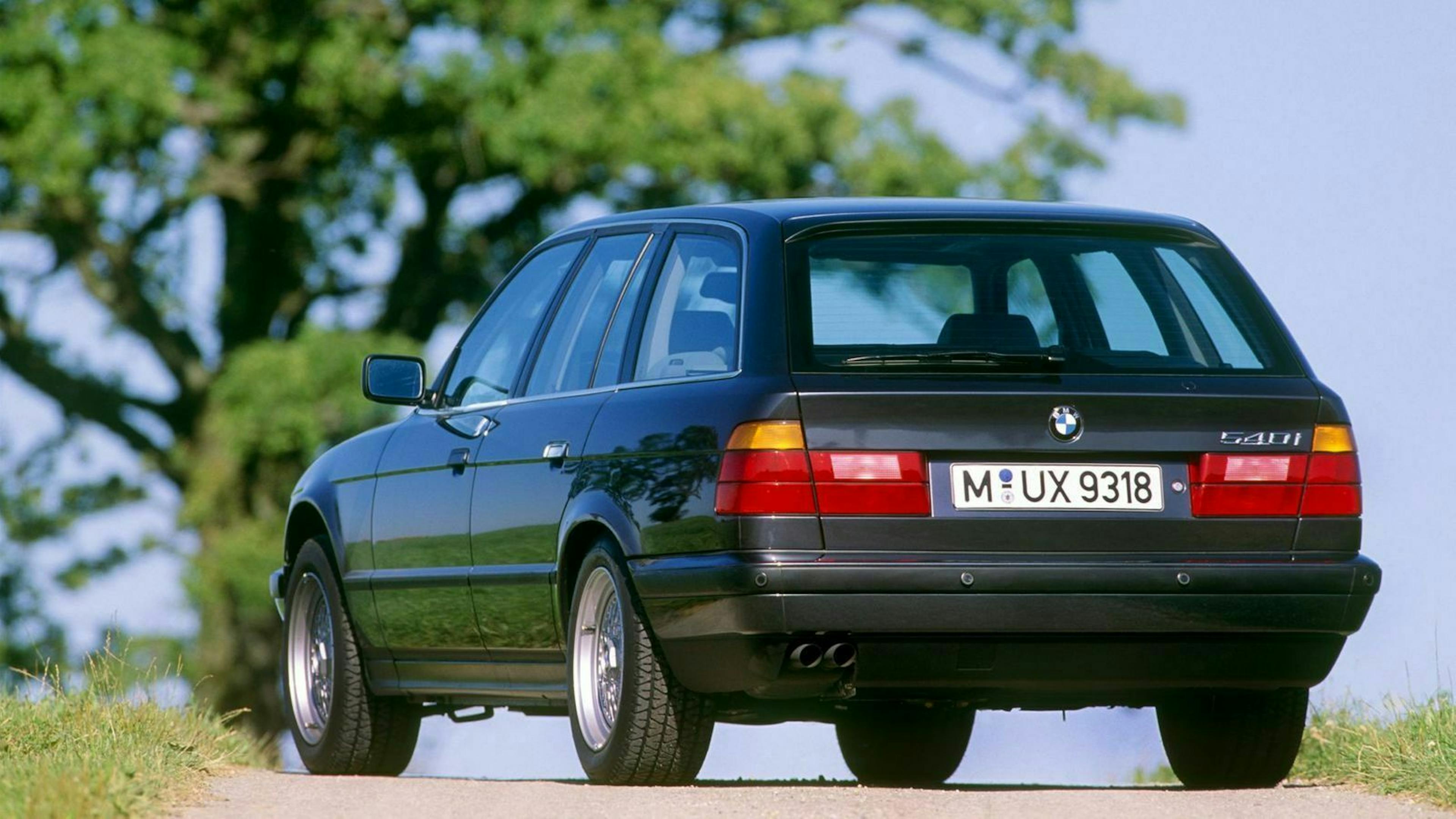 Ein schwarzer BMW 5er Touring Oldtimer steht vor einem Baum.