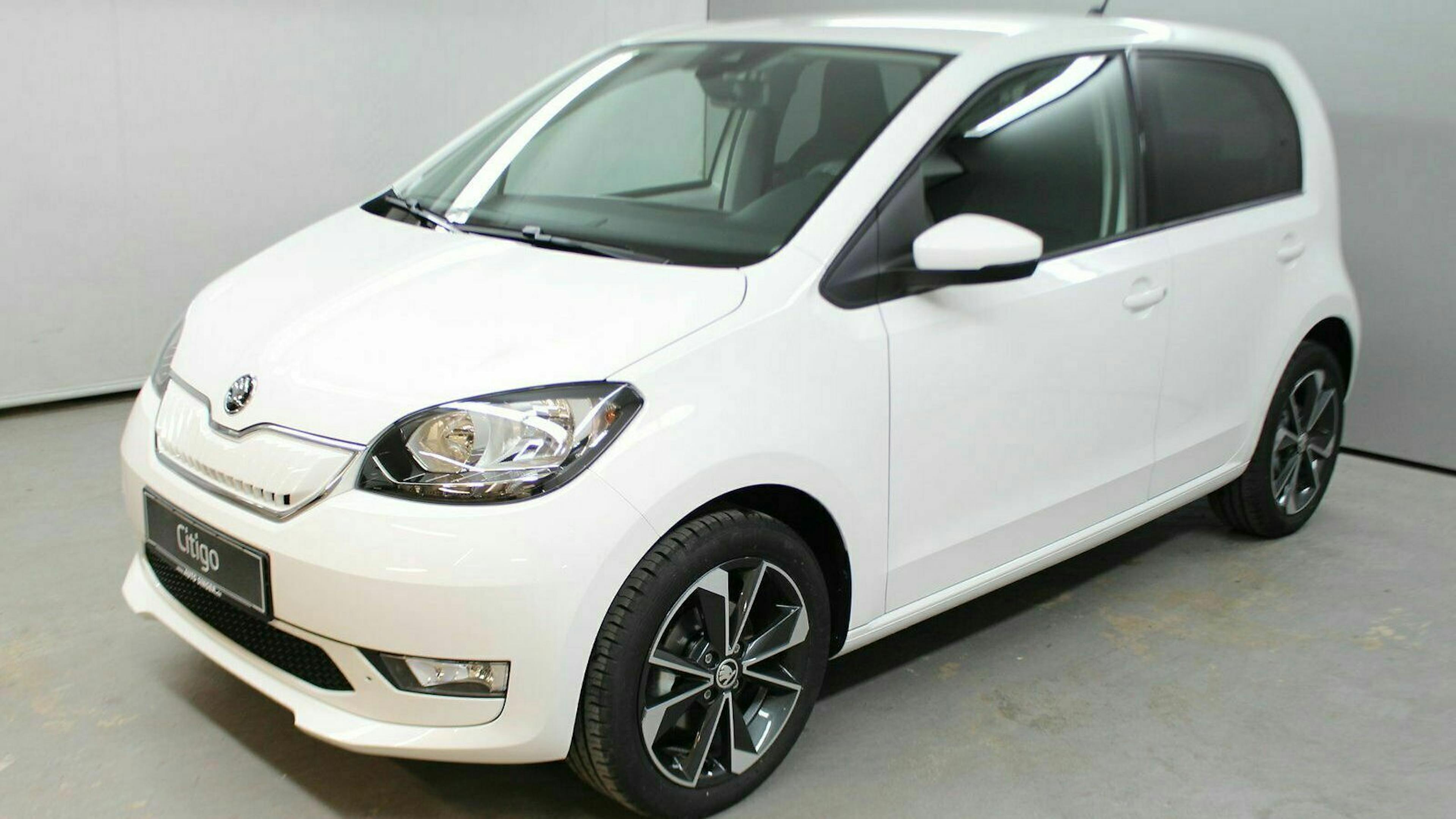 Weißer Kleinwagen in einem Studio, seitlich fotografiert. Fünf Türen, schwarze Felgen und moderne Beleuchtungselemente.