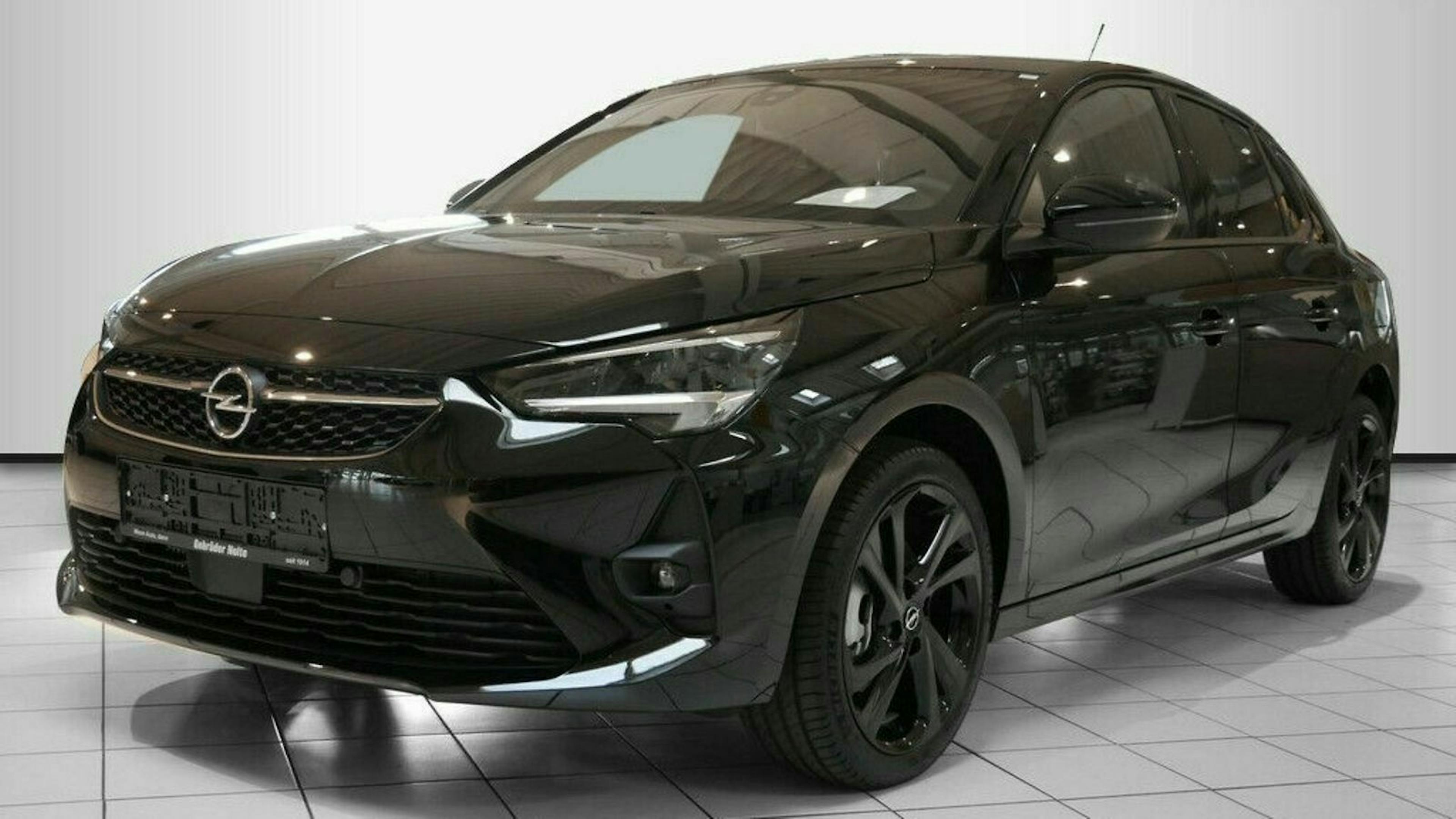 Schwarzer Opel Corsa, Front- und Seitenansicht auf weißem Hintergrund, in einem Ausstellungsraum mit glänzendem Boden.