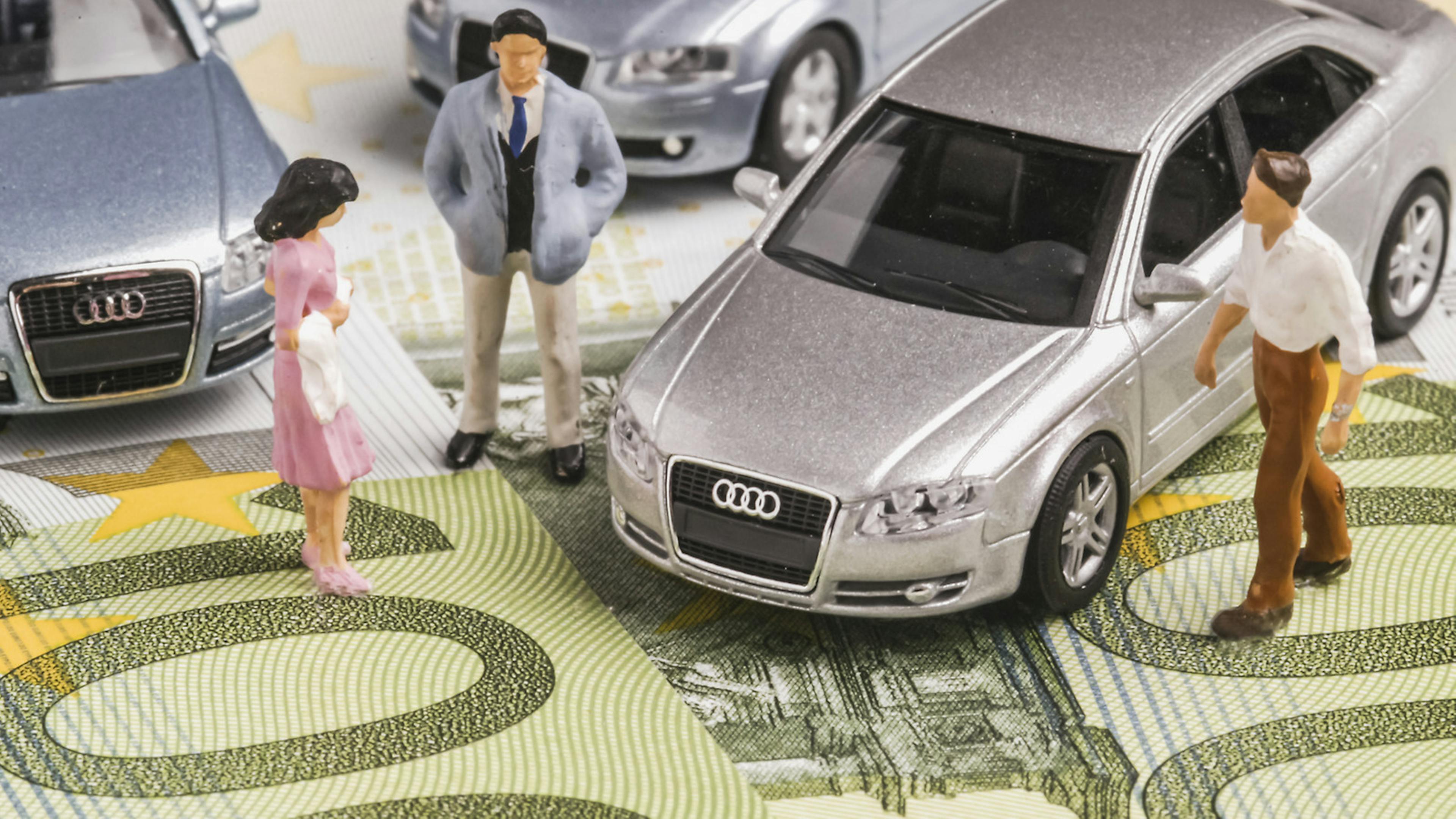 Modellfiguren stehen zusammen mit Modellautos auf einem 100-Euro-Schein