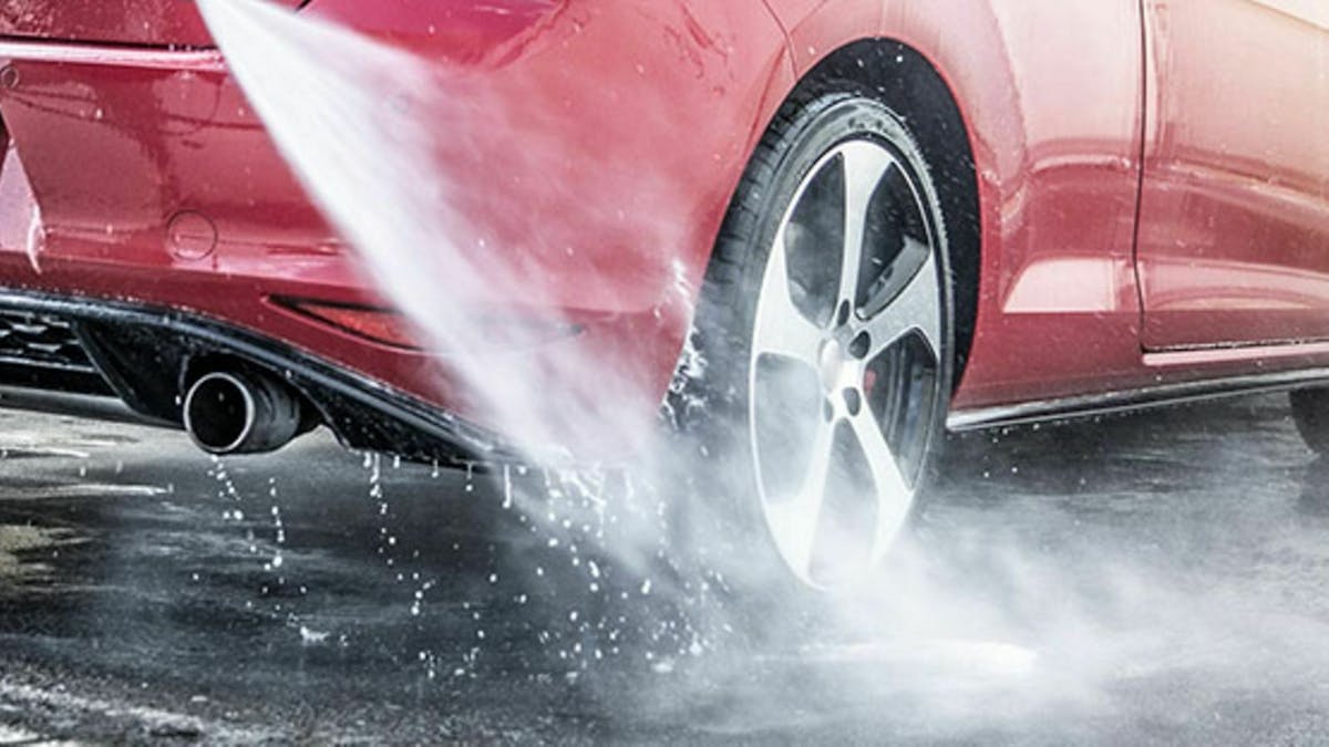 Jemamd sprüht den Heckbereich seines Autos gründlich ab.