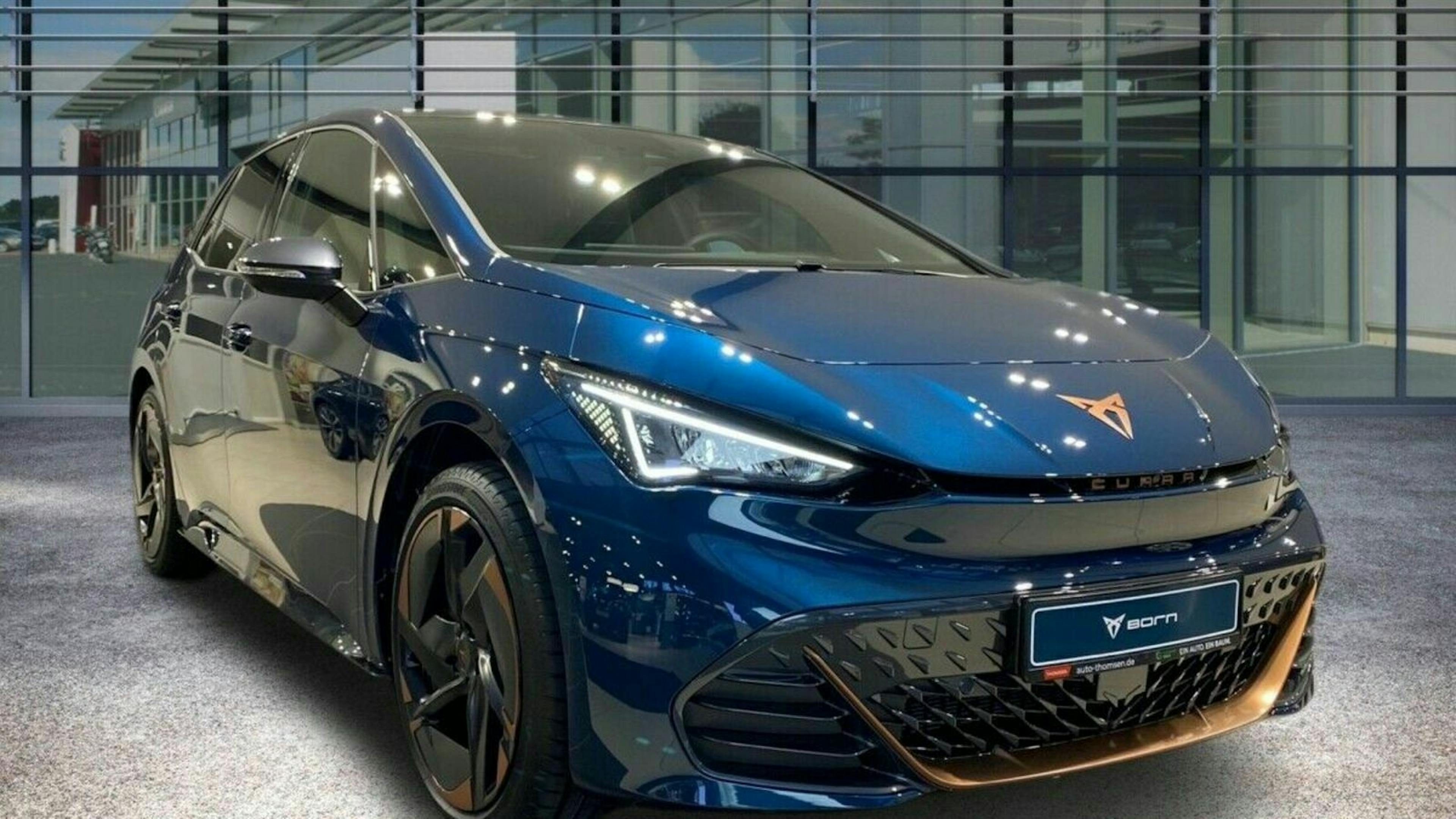 Ein dunkelblauer Cupra Born steht vor einem Gebäude mit Glasfassade