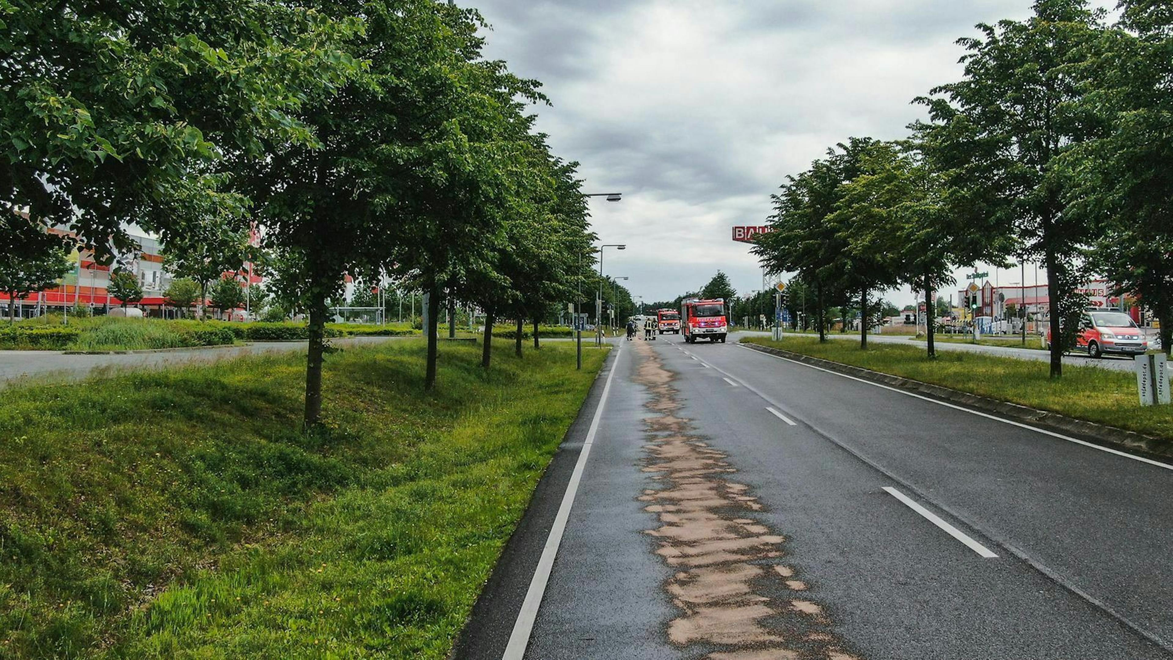 Die Feuerwehr entfernt mögliche Ölrückstände auf der Straße mithilfe eines Nassreinigungsverfahrens.
