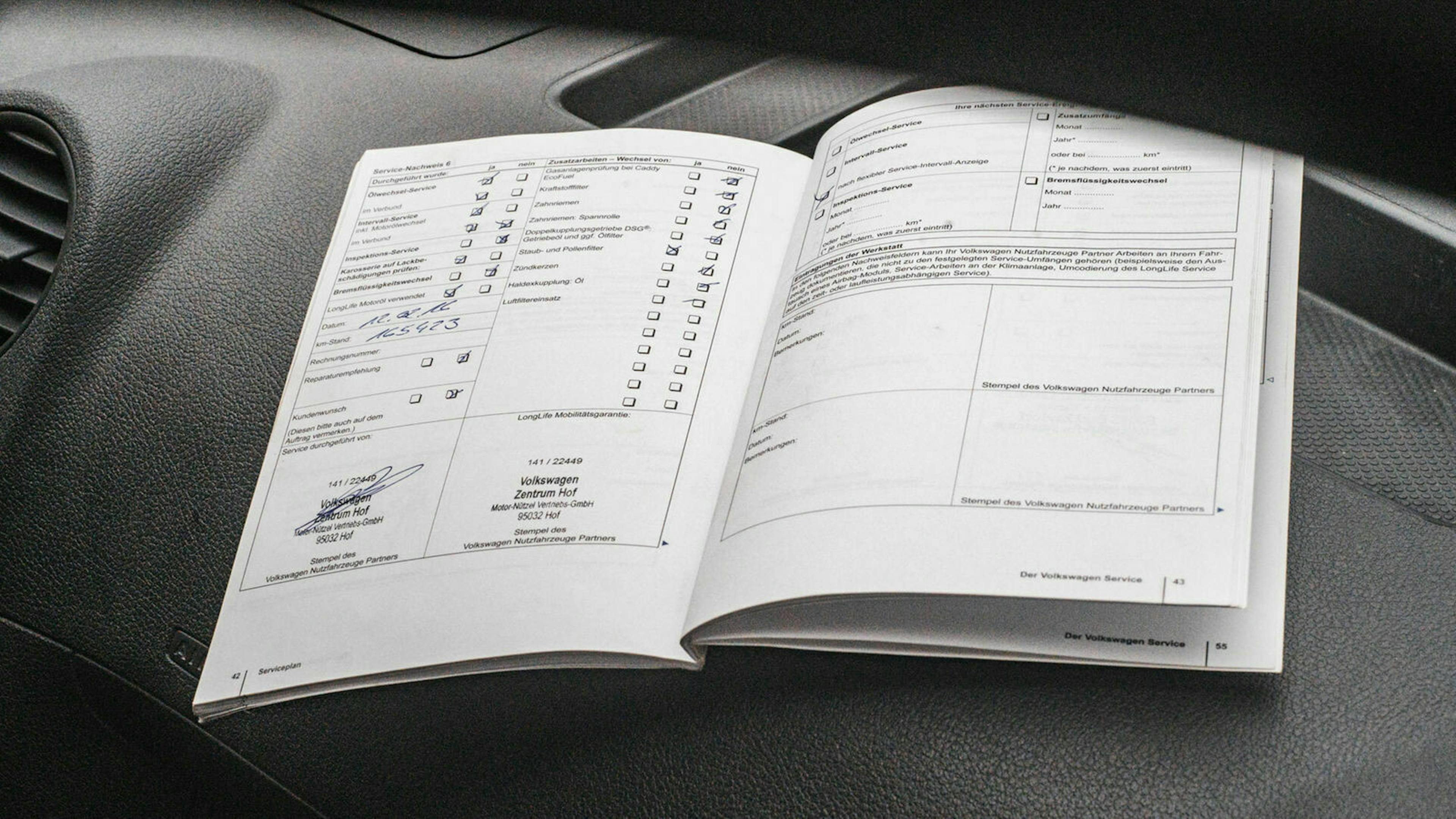 Ein aufgeschlagenes Scheckheft liegt auf dem Armaturenbrett eines Autos