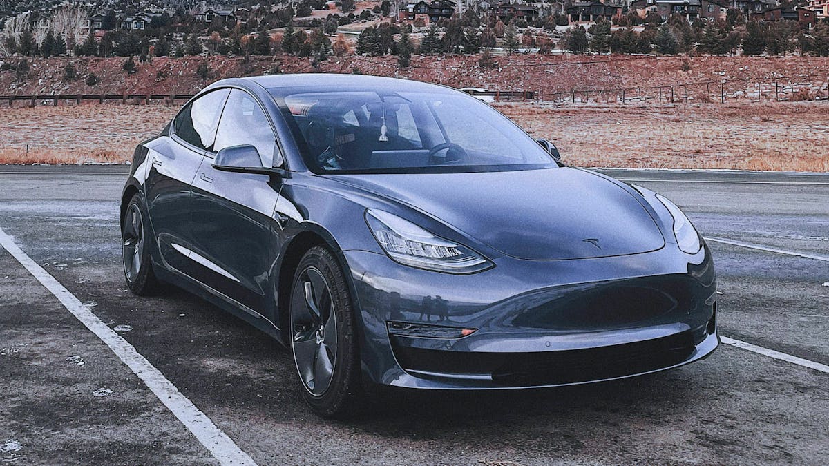 Ein dunkelgraues Tesla Model drei steht auf einem Parkplatz