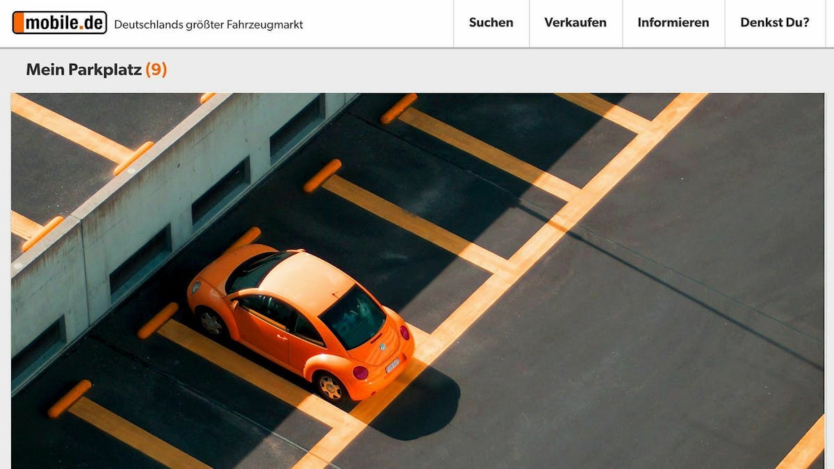 Zu sehen ist ein Parkplatz mit einem orangenen Beetle