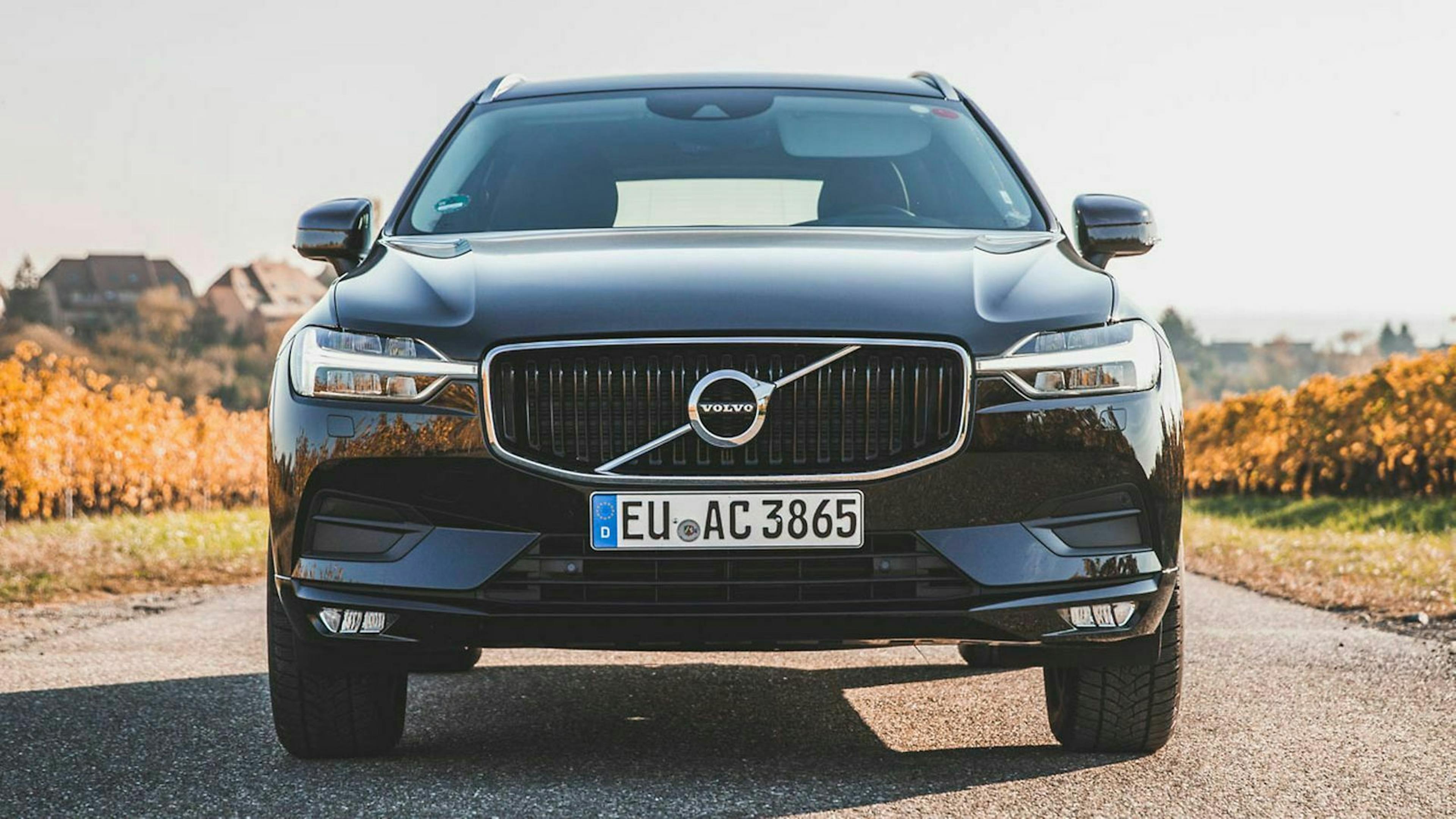 Ein schwarzer Volvo XC60 von der Autovermietung Avis steht im Sonnenlicht auf eine Landstraße.