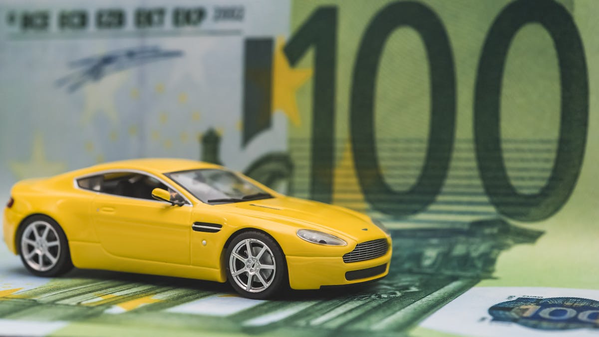 Das Modell eines gelben Sportwagens steht auf einer 100-Euro-Banknote.