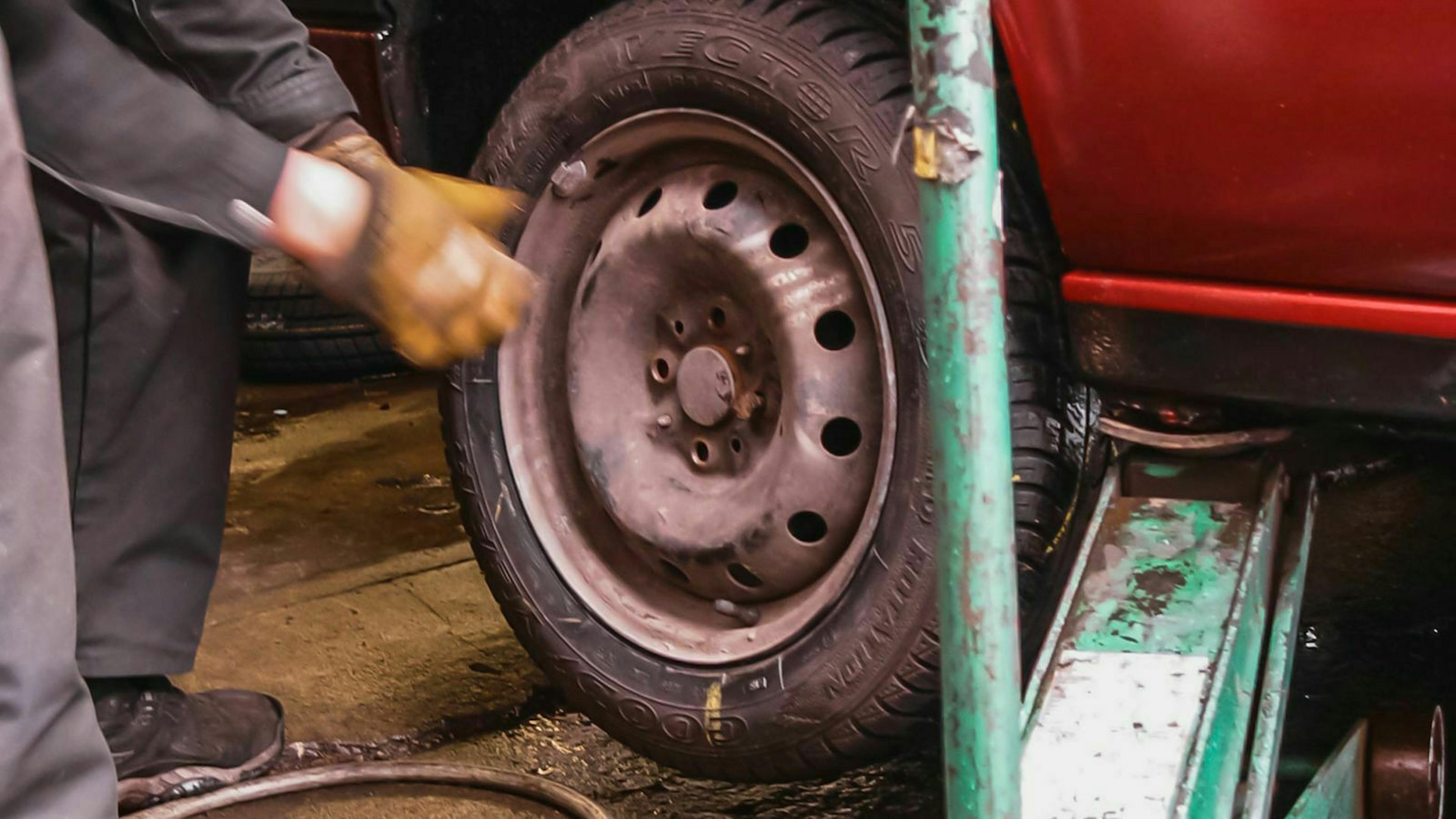 Ein hydraulischer Wagenheber wird an die dafür vorgesehenen Aufnahmepunkte unterm Auto angesetzt.