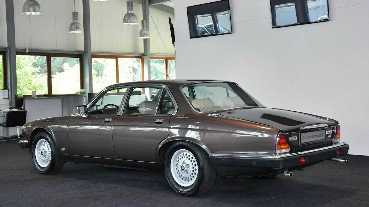 Grauer Jaguar XJ12 im Showroom stehend in der Ansicht von hinten-links