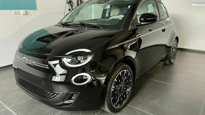 Ein schwarzer Fiat 500 Elektro steht in einer weiß gestrichenen Garage an einer Ladebuchse