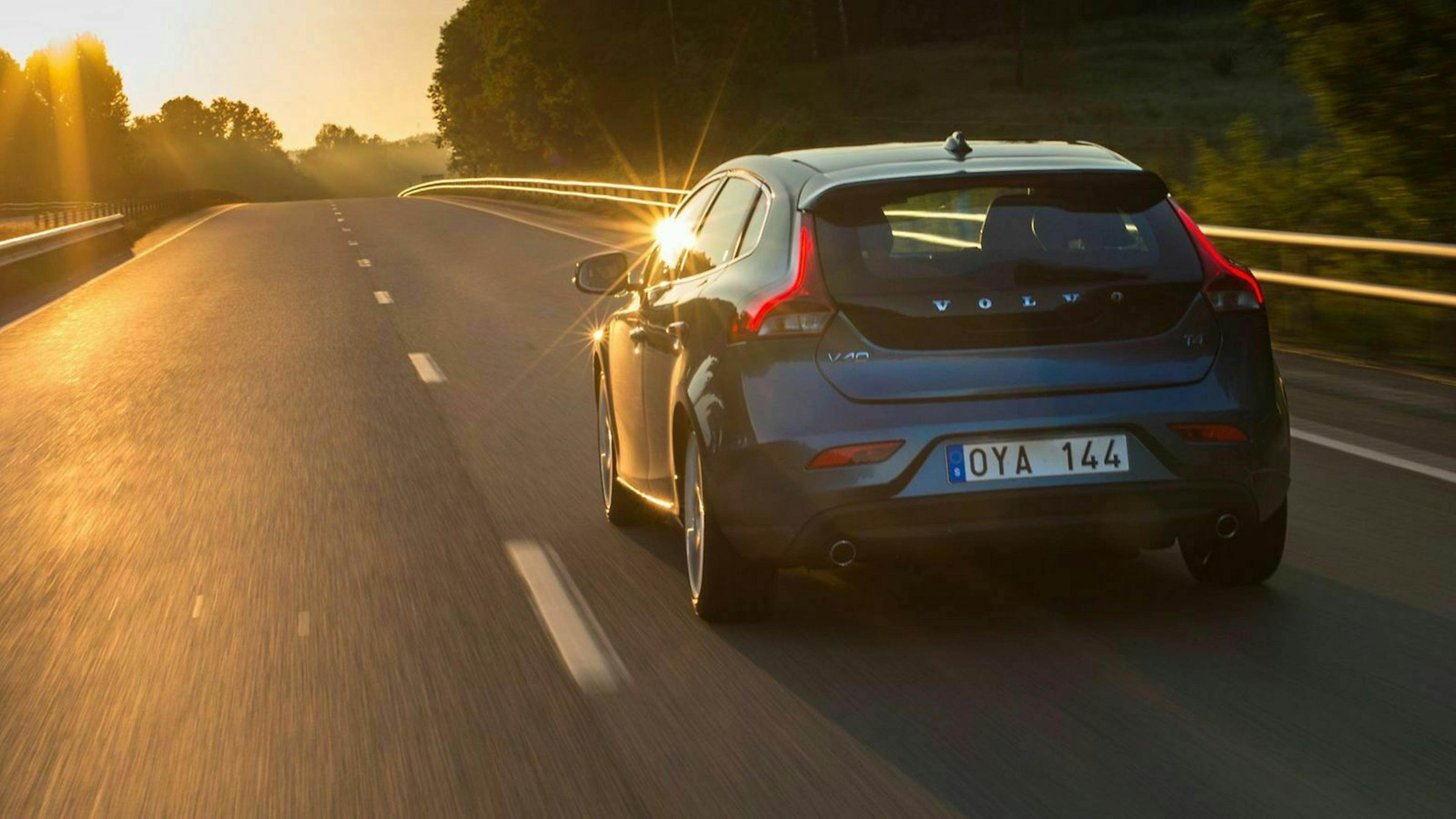 Volvo V40 in der Heckansicht, fahrend in Richtung eines Sonnenuntergangs