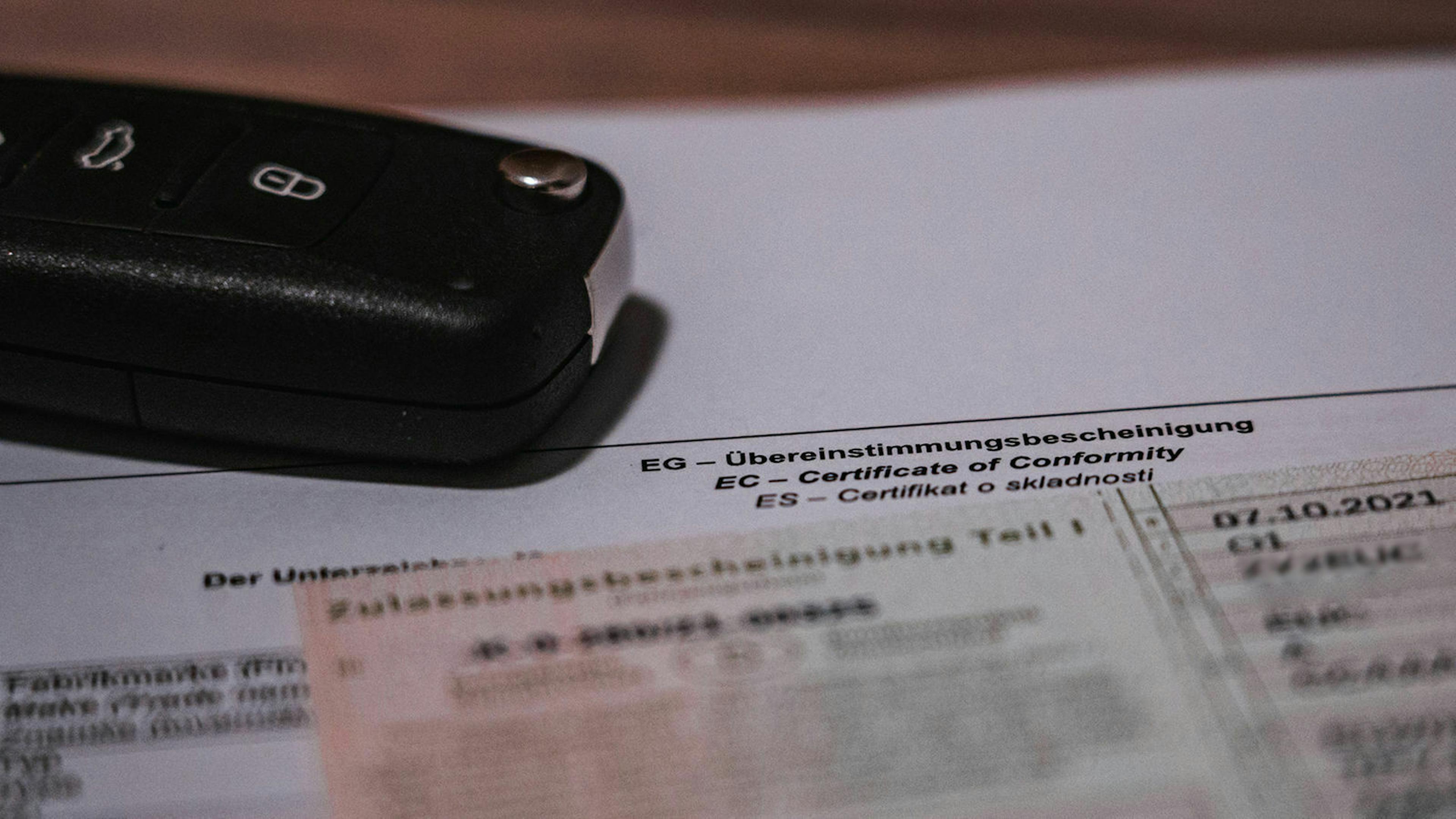 Ein Autoschlüssel  und die Zulassungsbescheinigung Teil 1 liegen auf einem CoC-Papier
