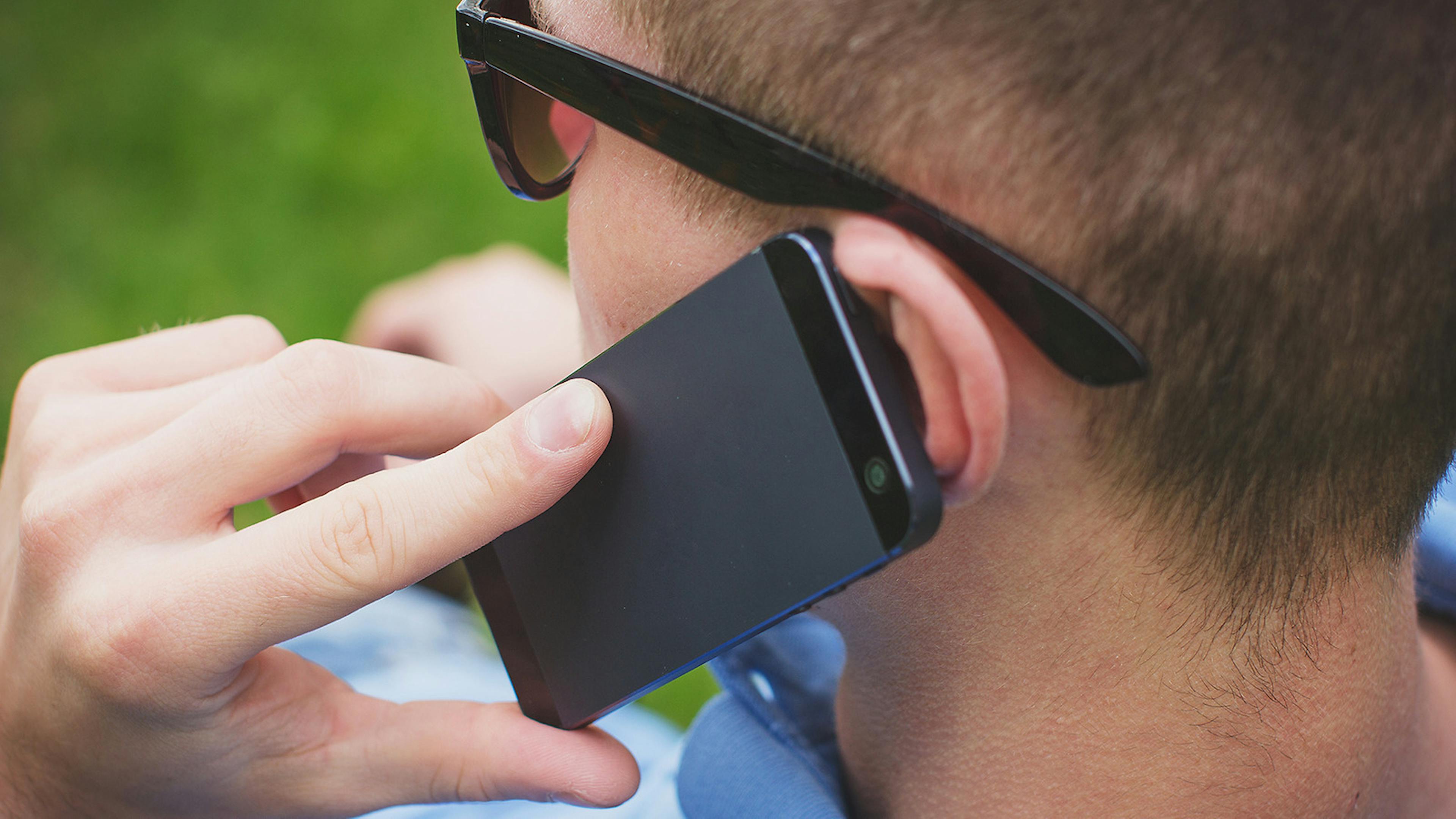 Ein Mann telefoniert mit einem Smartphone am Ohr.