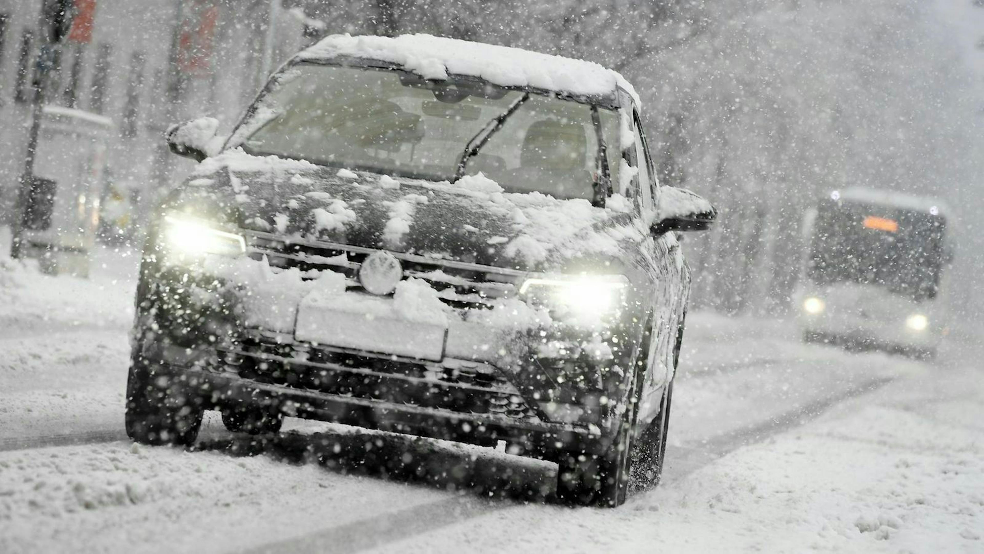 Ein Auto wird in einer Winterlandschaft von einem Bus verfolgt