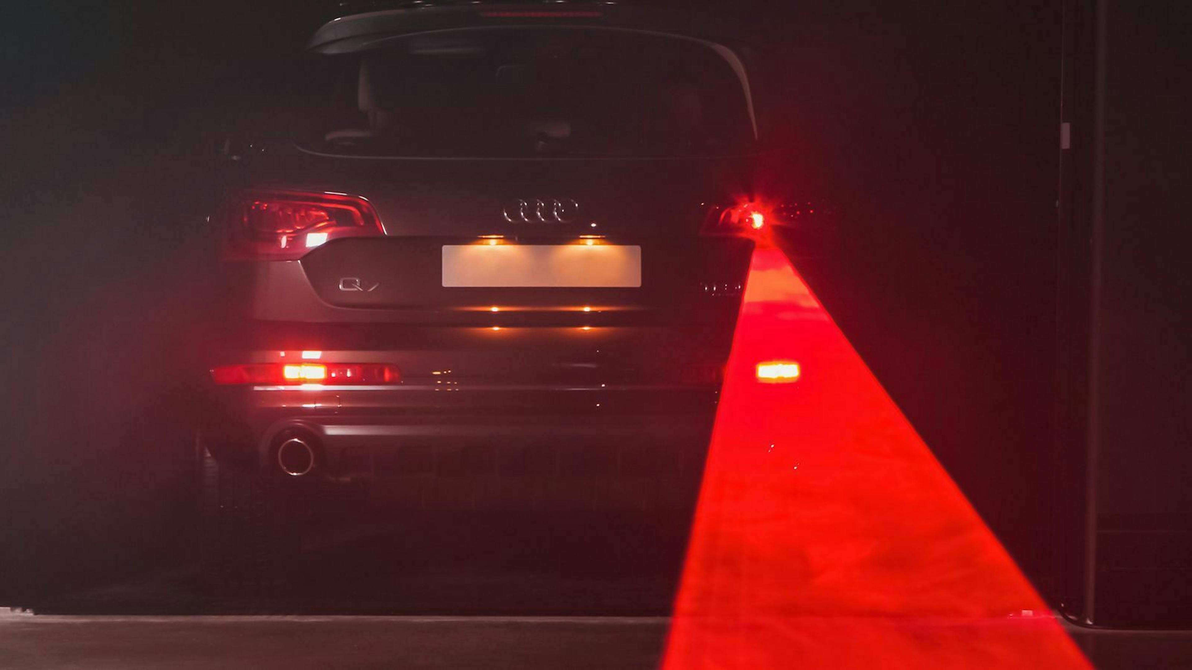 Ein roter Lichtkegel scheint aus der rechten Rückleuchte eines Audi Q7.