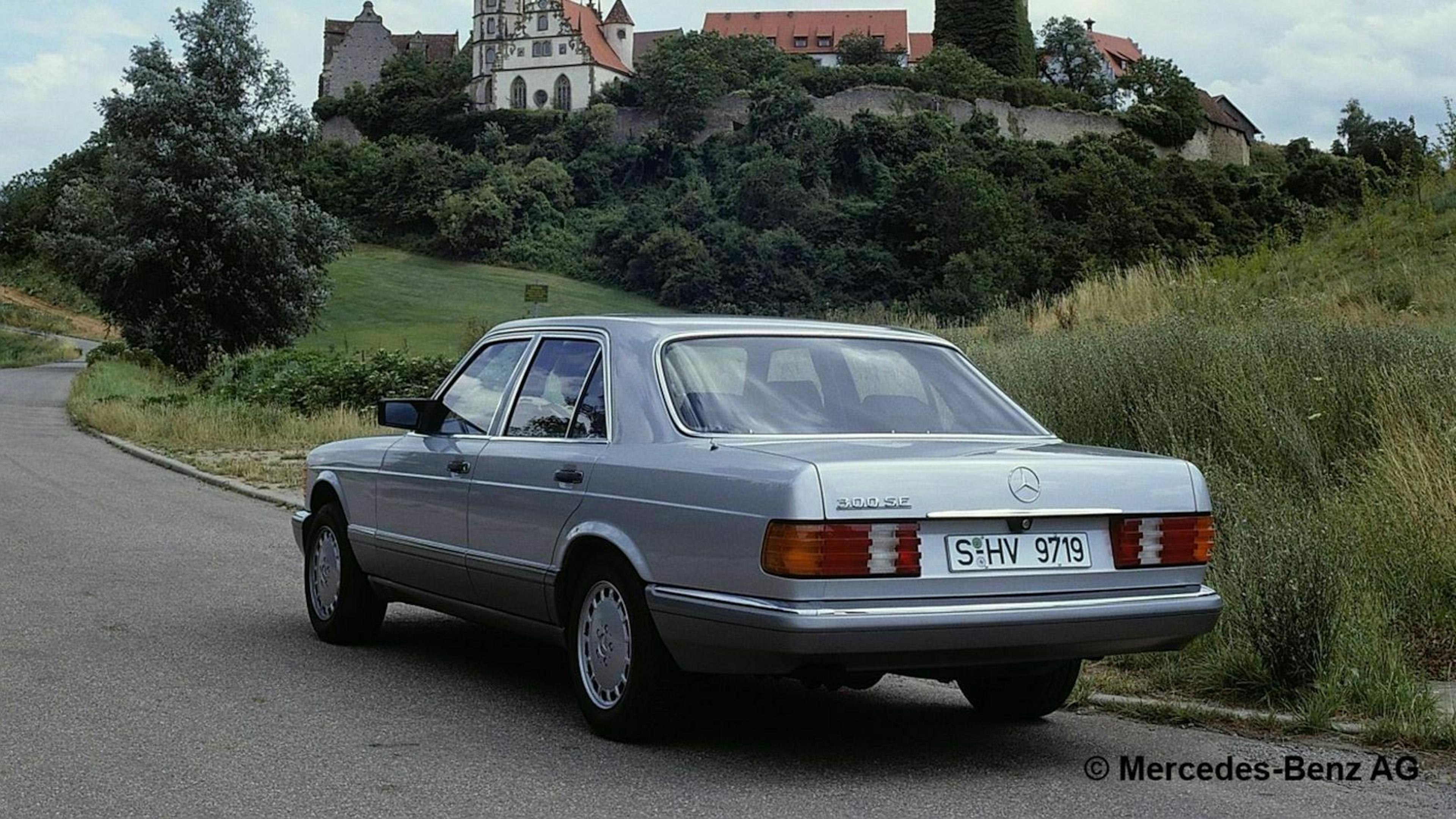 Mercedes W126 fahrend in seitlicher Heckansicht
