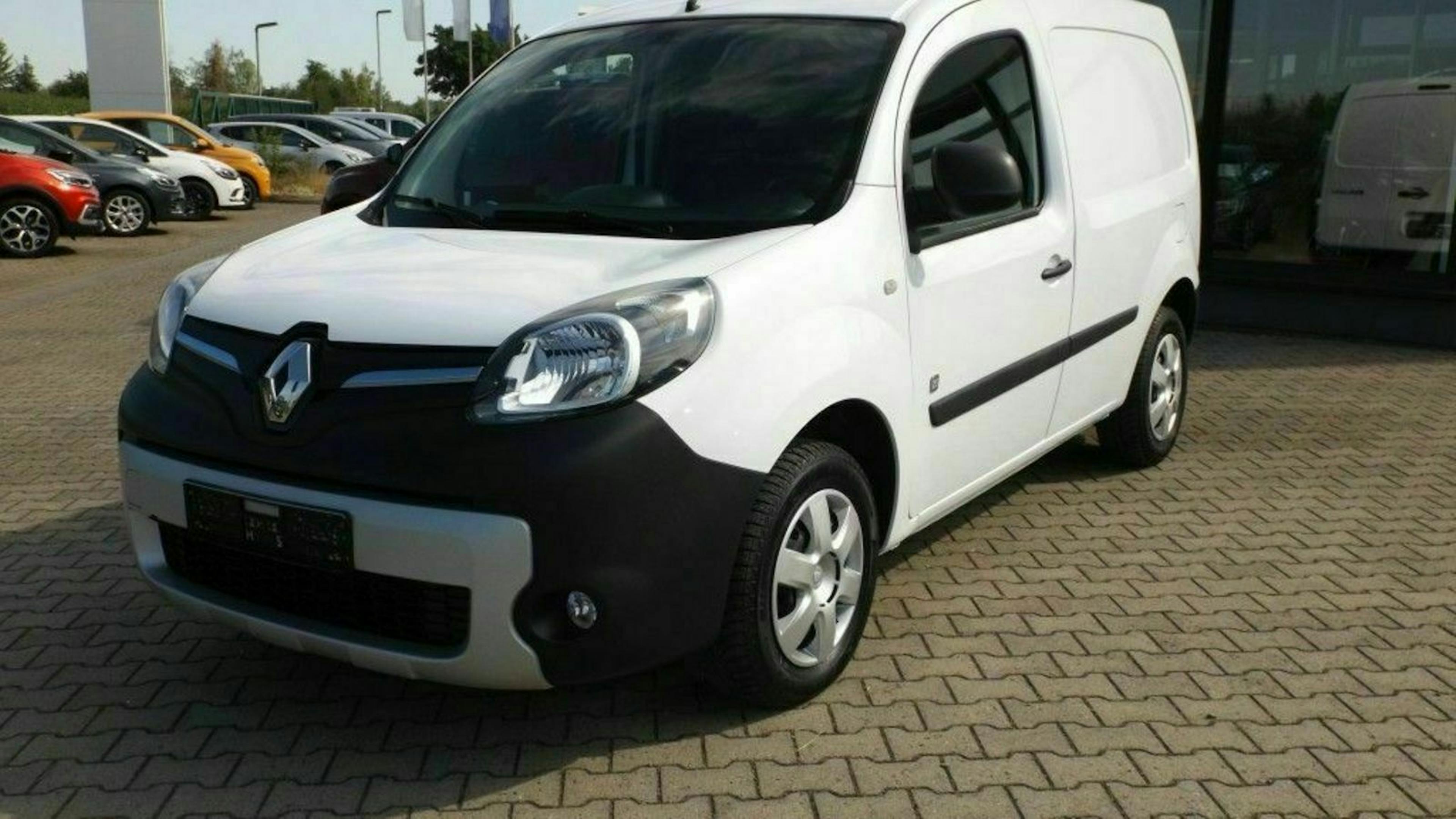 Ein weißer Renault Kangoo Z.E. steht auf einem Parkplatz vor einem Gebäude mit Glasfront