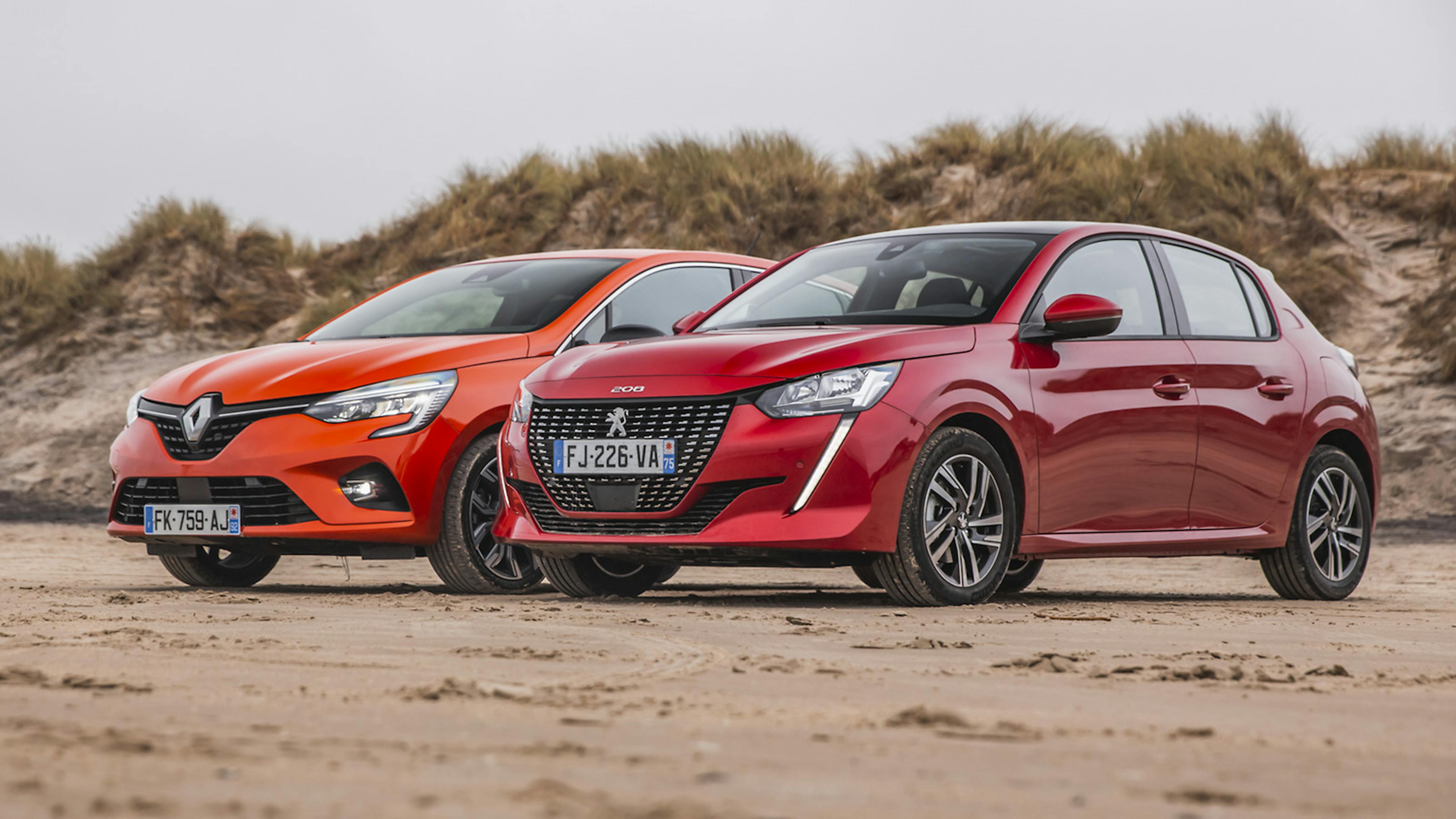 Roter Peugeot 208 am Strand stehend vor einem Renault Clio