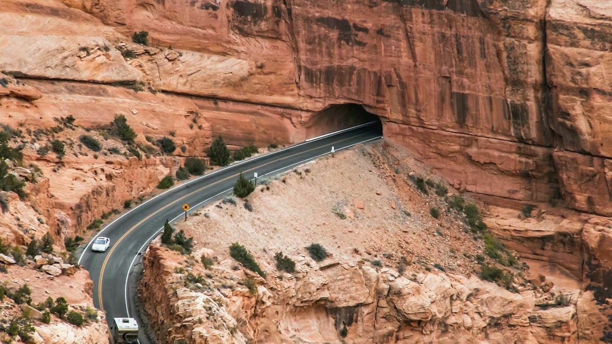 Eine Straße führt in den Rocky Mountains in einen Tunnel.