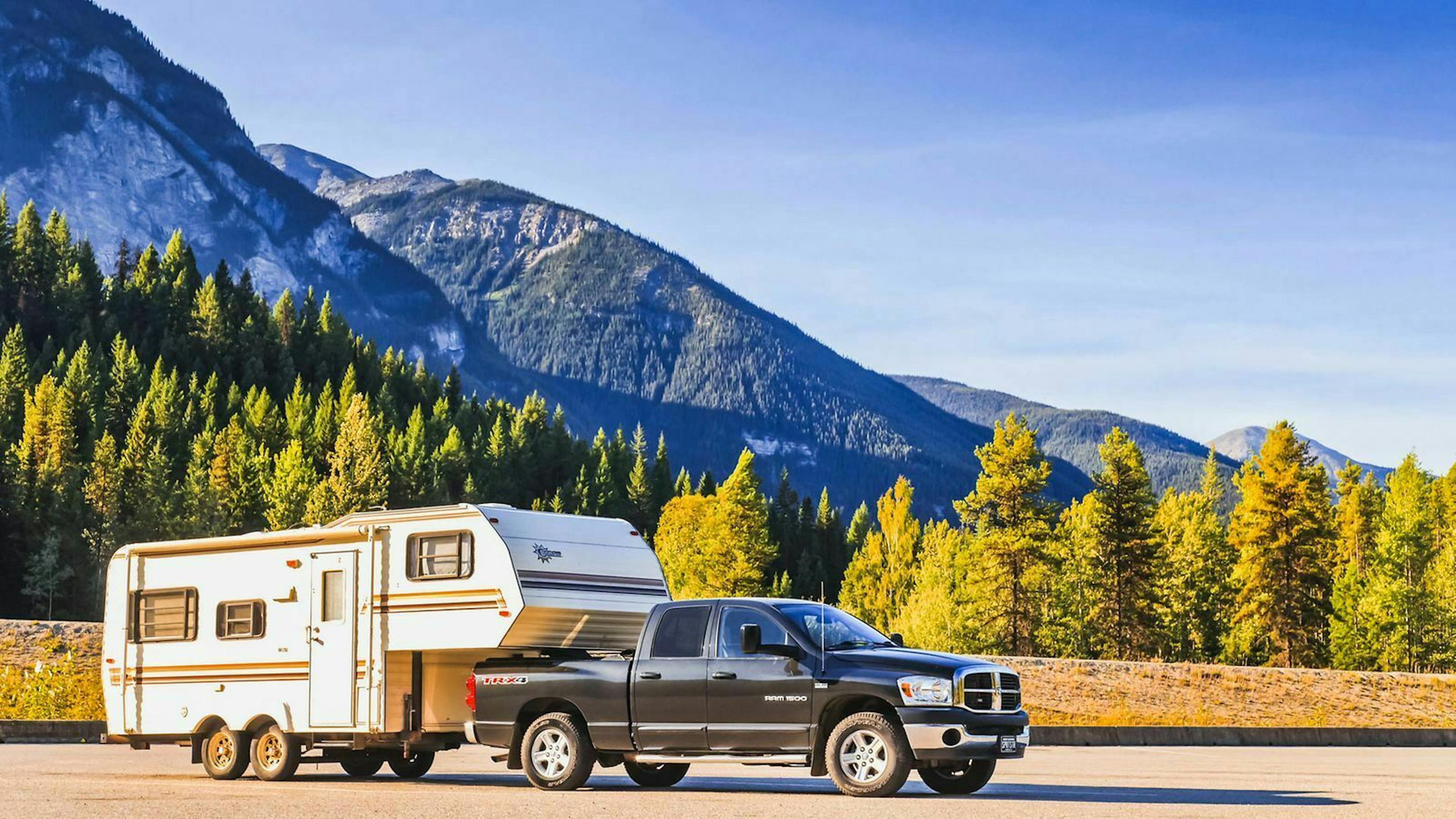 Ein Pickup-Truck zieht einen Anhänger mit Kupplung auf der Ladefläche hinter sich her.