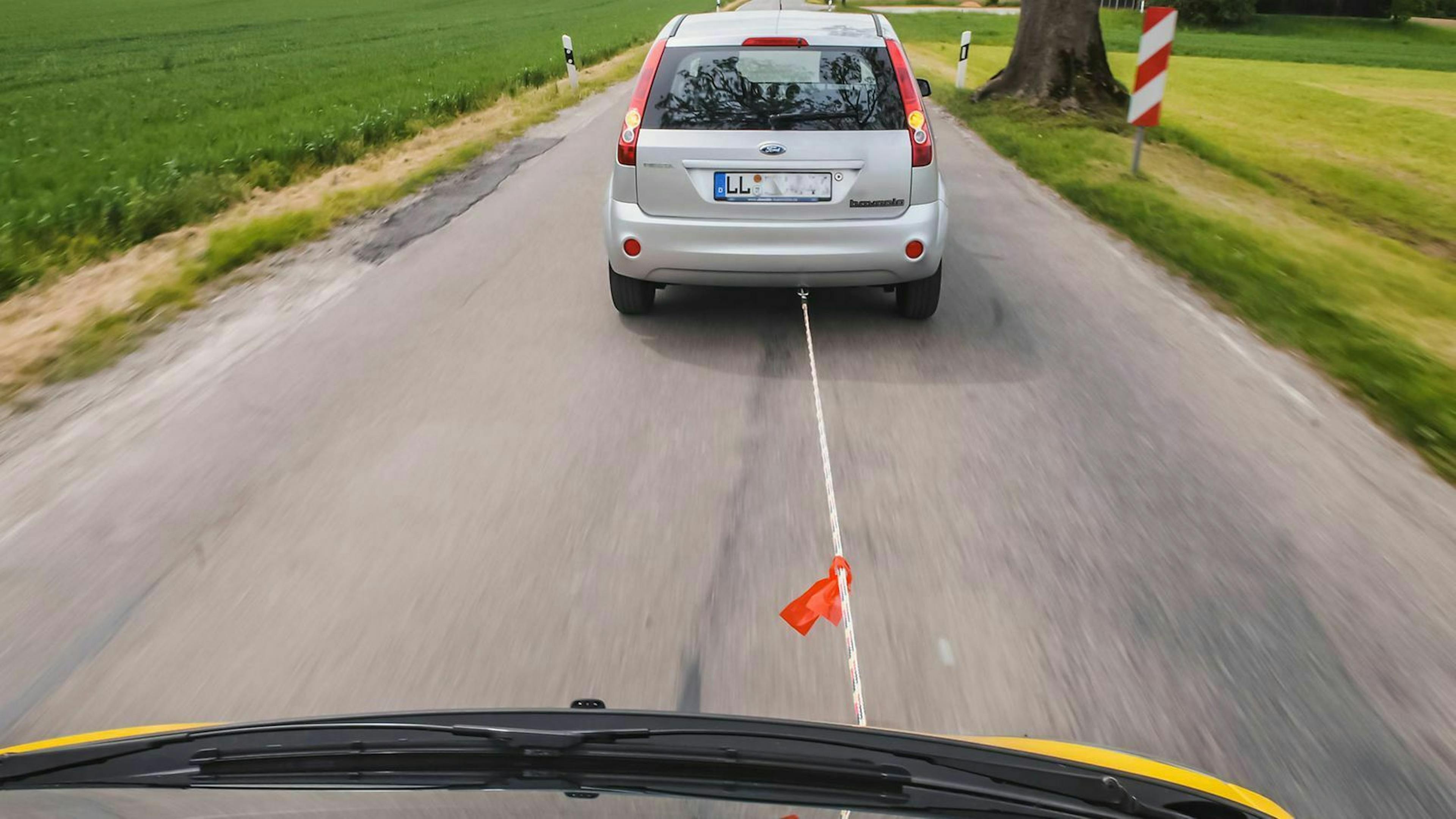 Aus der Perspektive des abgeschleppten Autos blickt man auf das Abschleppseil und das Zugfahrzeug.