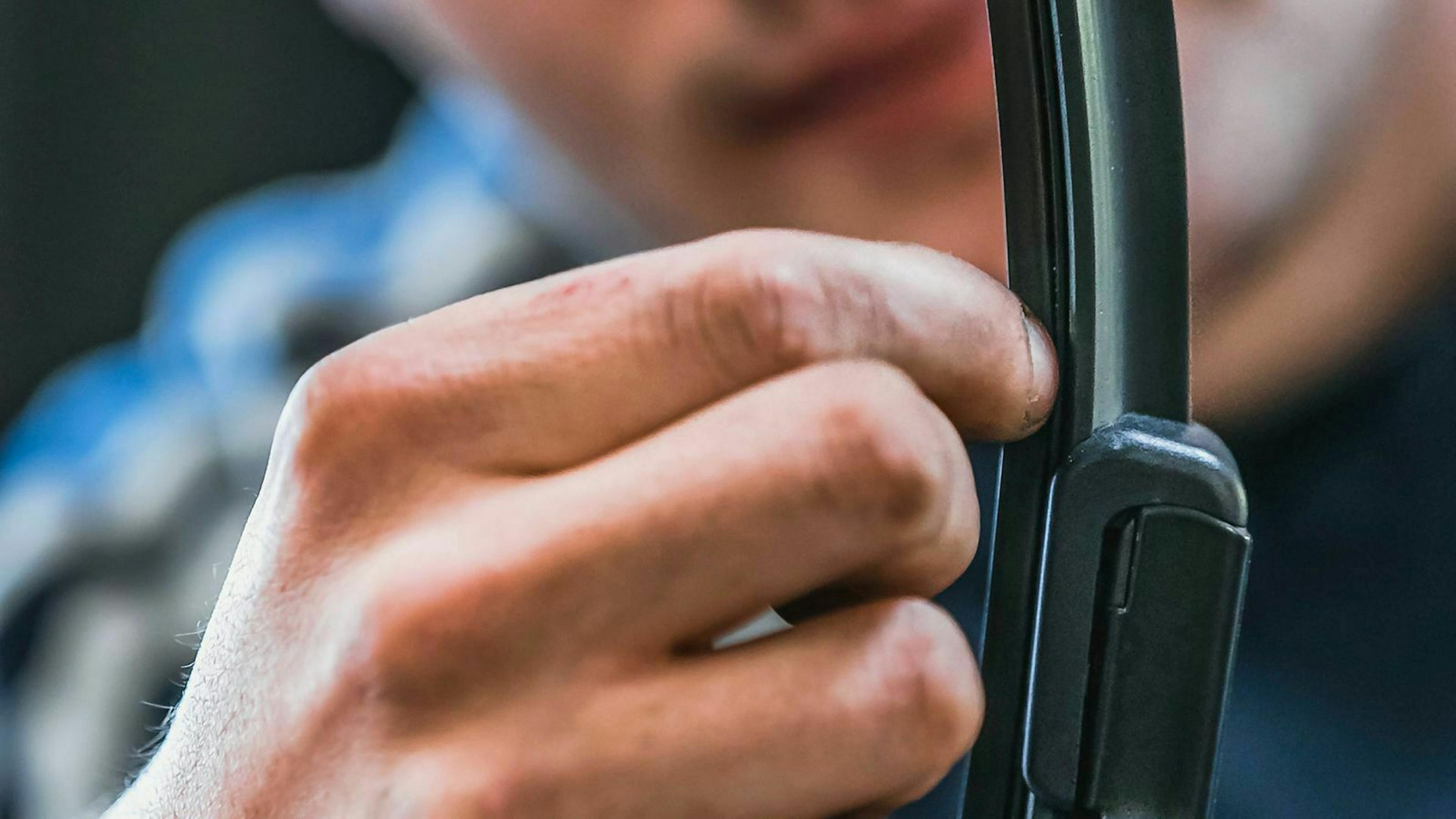 Jemand kontrolliert die Gummilippe eines Scheibenwischers.