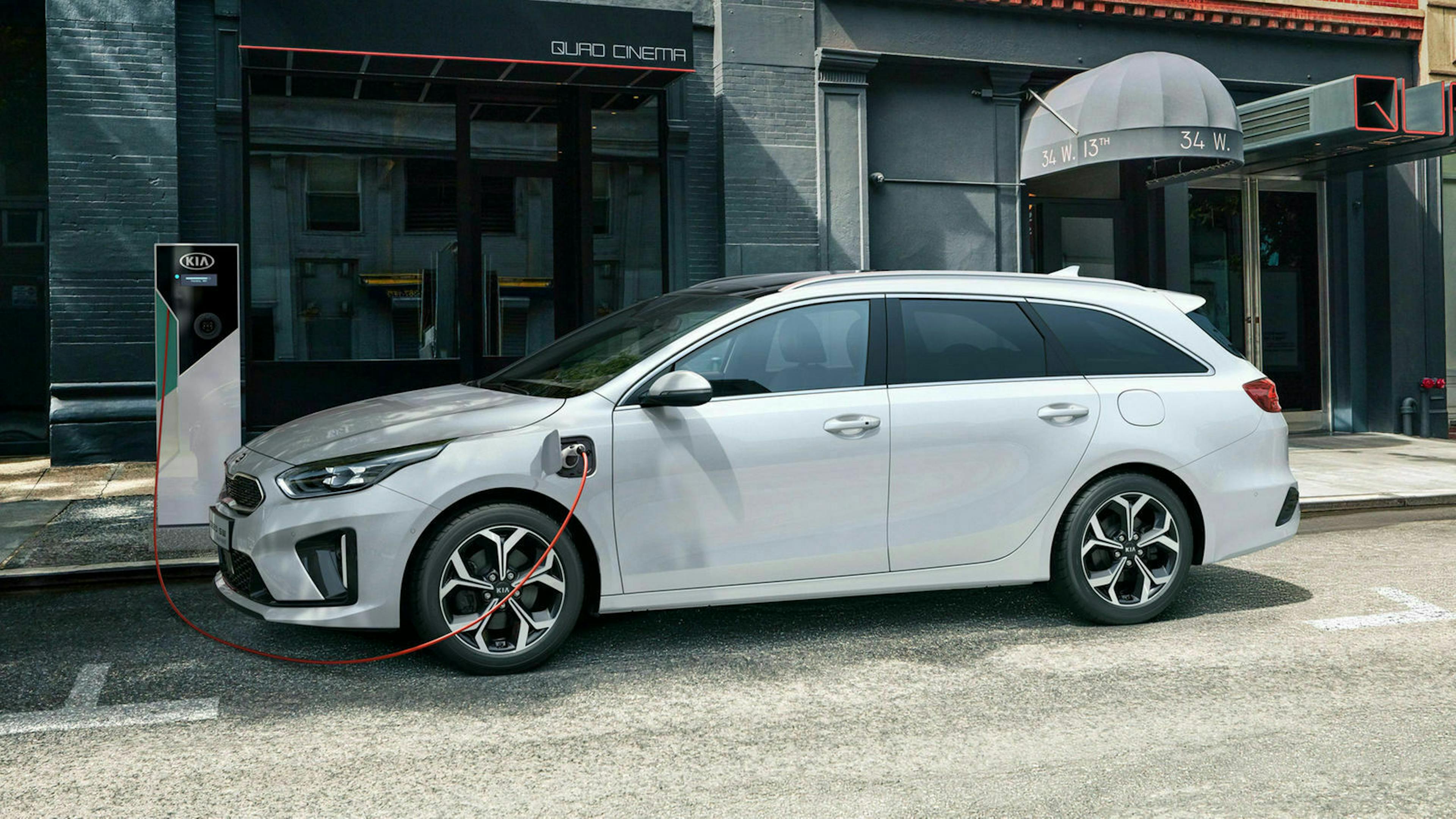 Ein weißer Kia Ceed Sportswagon 1.6 GDI Plug-in-Hybrid steht an einer Ladesäule in der Innenstadt und lädt den Akku