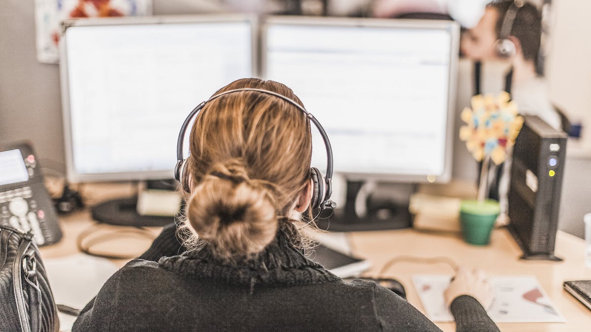 In einem Callcenter sitzt jemand vor zwei Computer-Bildschirmen.