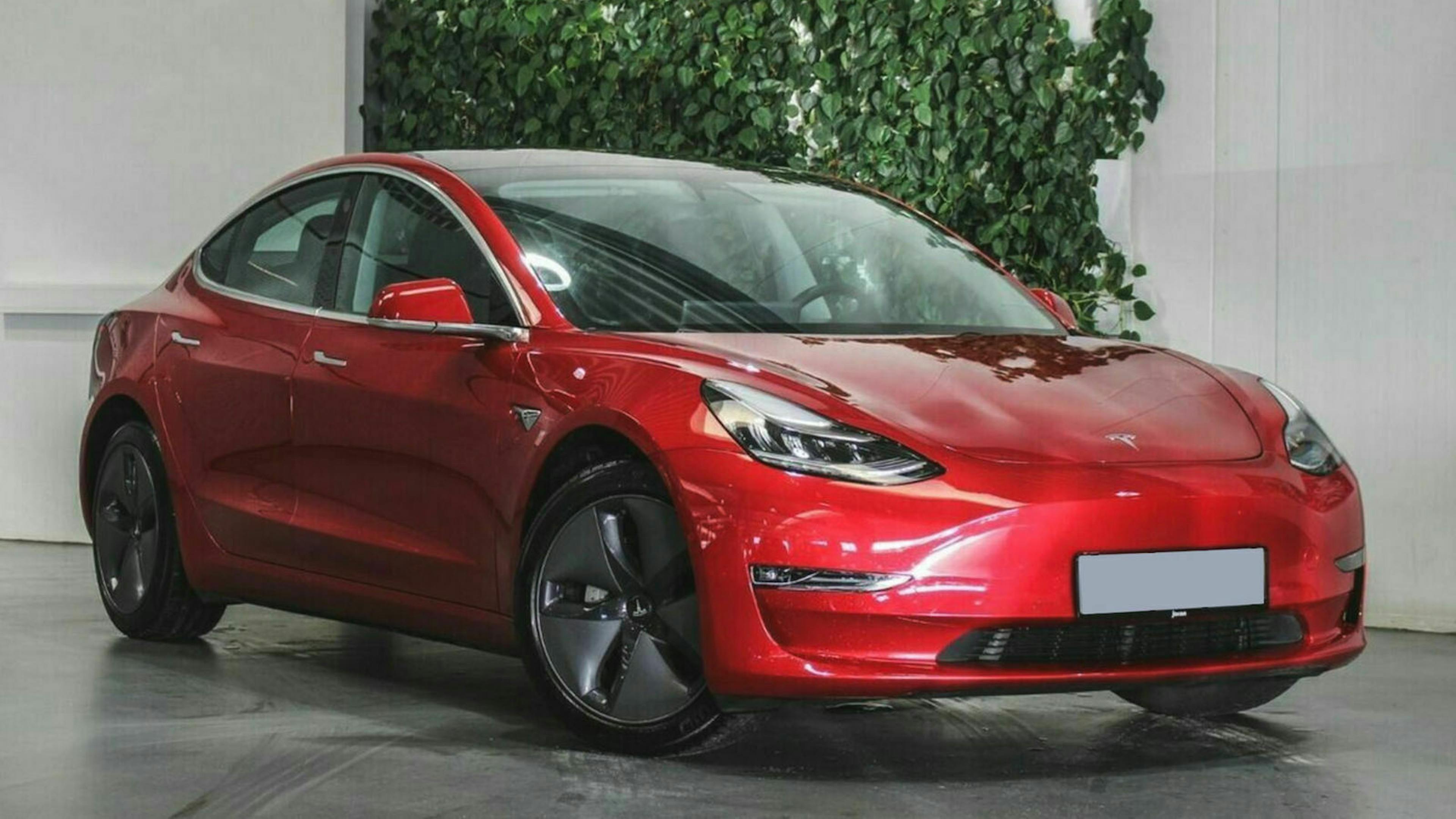 Ein roter Tesla Model 3 steht im Showroom eines Autohauses
