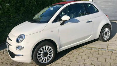 Ein weißer Fiat 500 Cult steht in einer Grundstücksauffahrt