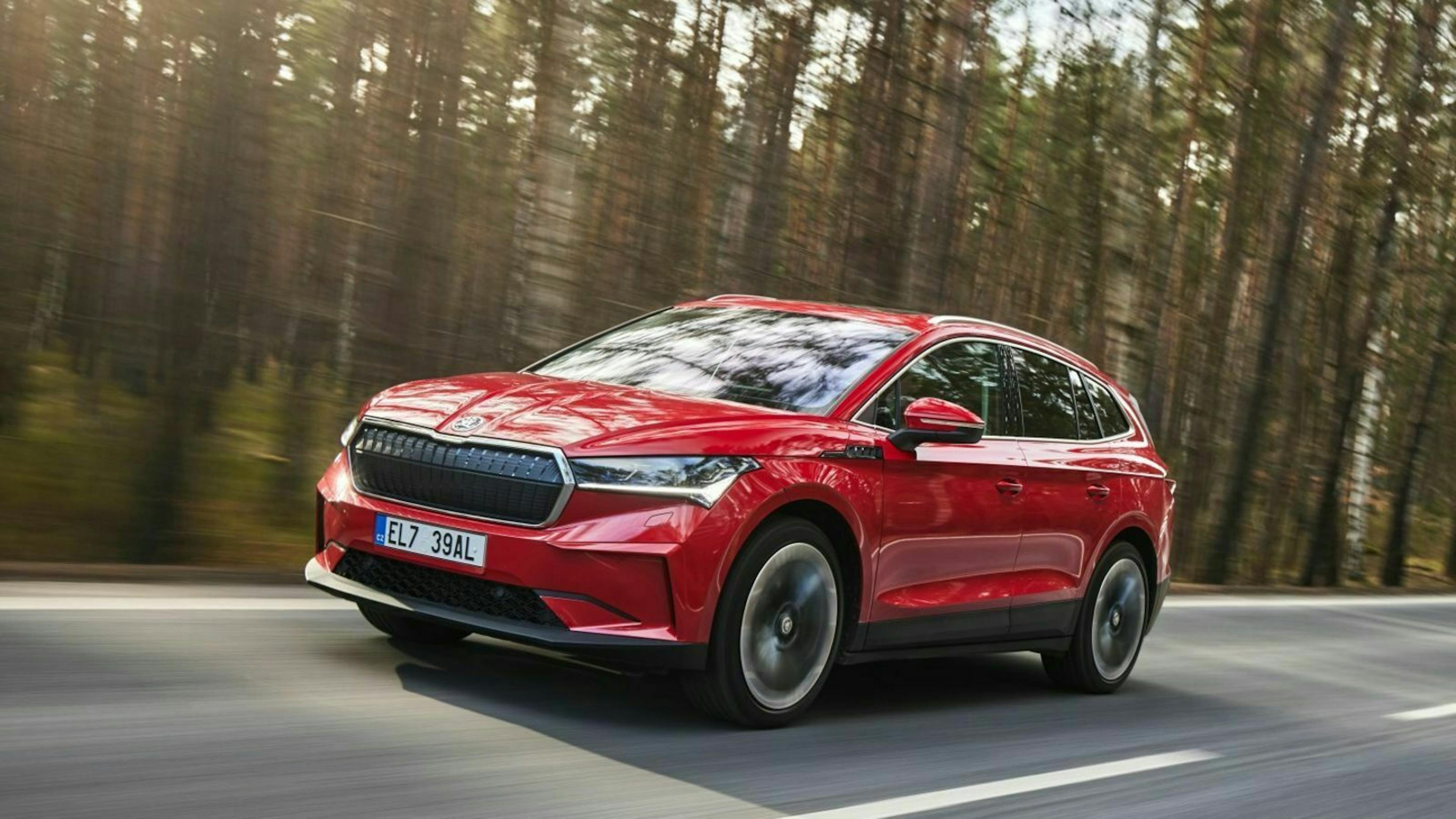 Ein roter Skoda Enyaq iV fährt eine Landstraße entlang an einem Wald vorbei