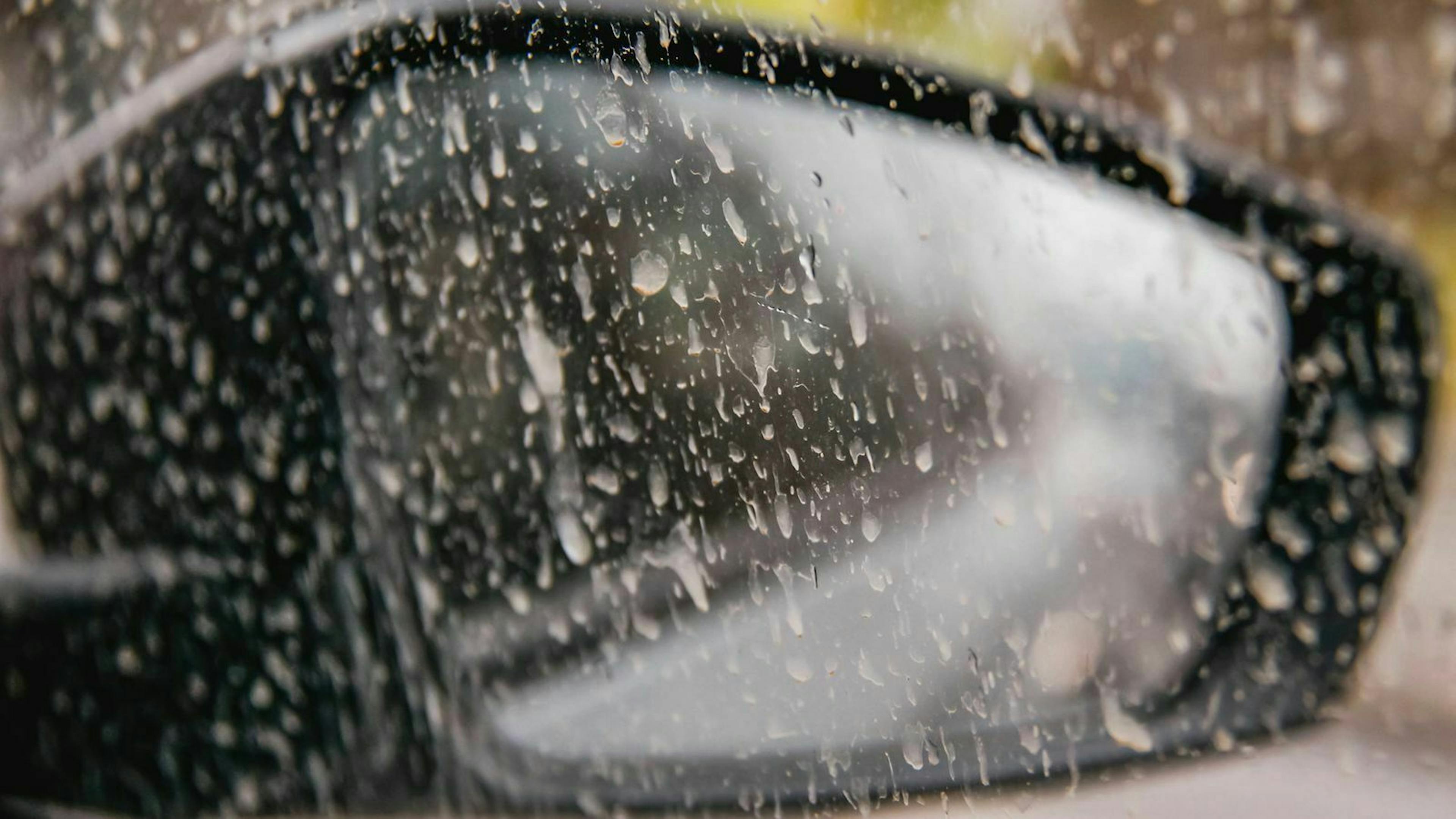 Ein schmutzige Autoscheibe mit Blick auf den Rückspiegel der Fahrerseite.