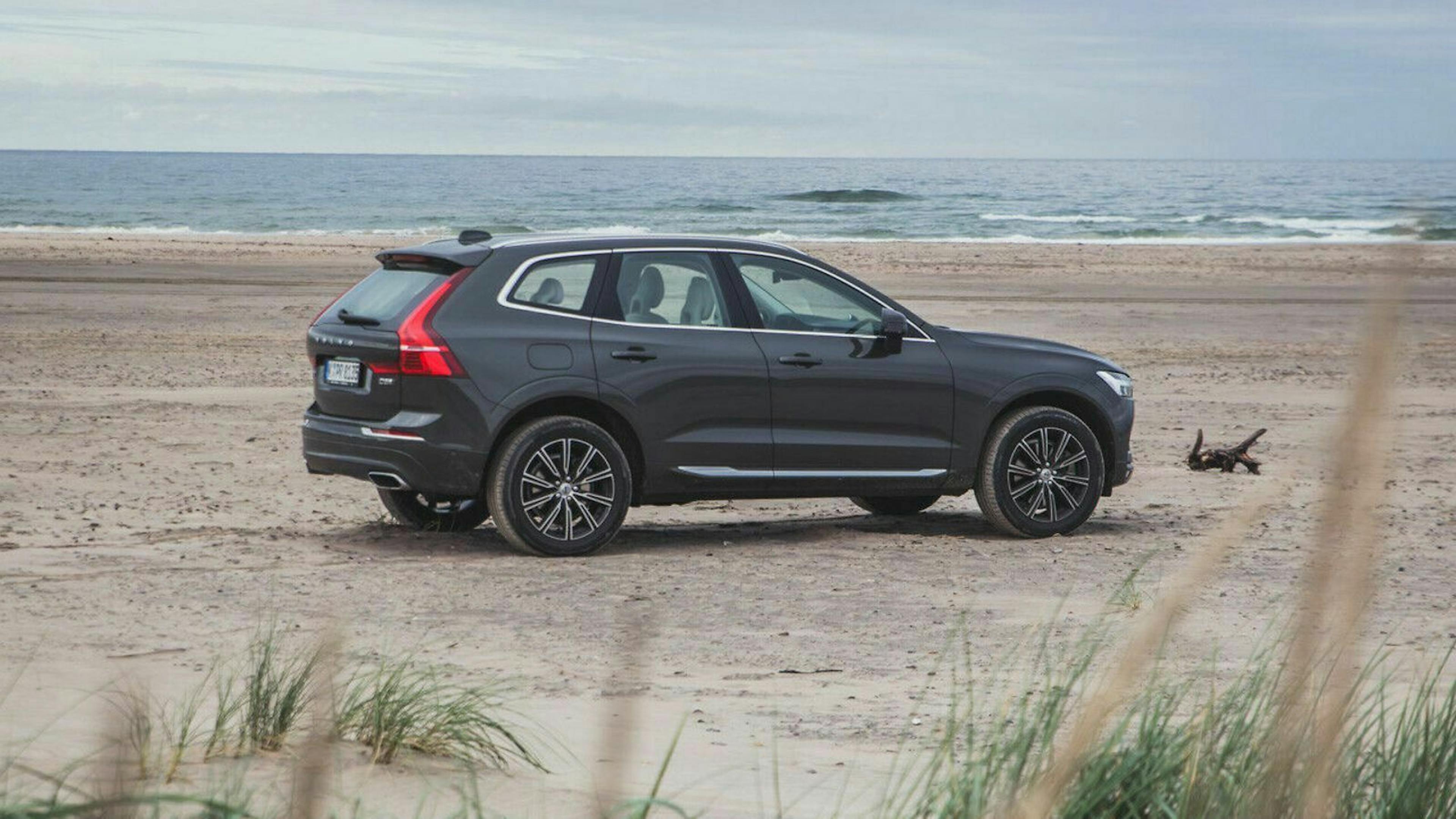 Seitenansicht des Volvo XC60 stehend am Strand. Im Hintergrund ist das Meer zu sehen.