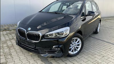 Ein schwarzer BMW 2er Active Tourer steht vor einem Gebäude mit grauer Fassade
