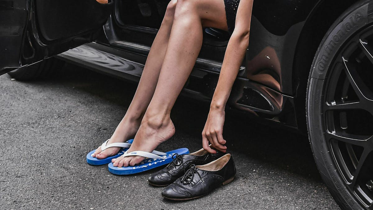 Jemand wechselt vor dem Autofahren von Flipflops auf feste Schuhe